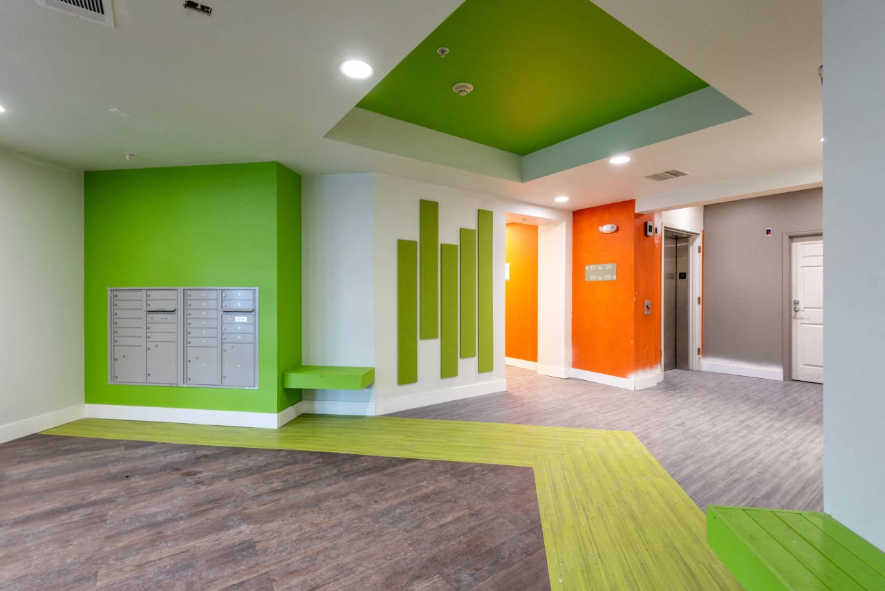 Vibrant lobby Lobby with community mail boxes and bright green and orange painted walls, bright green bench, wood like flooring