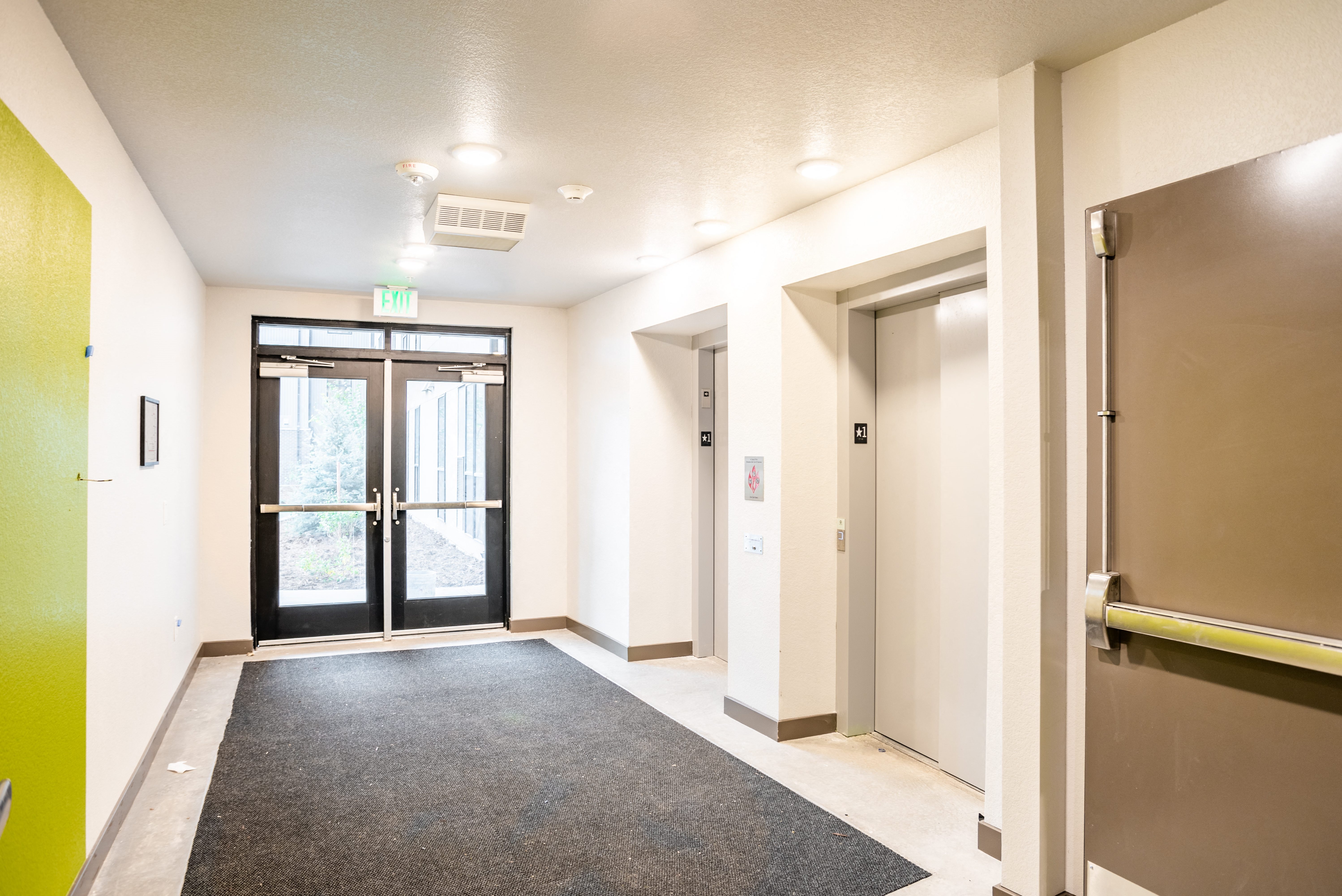 Elevator corridor with 2 elevators with glass doors to playground