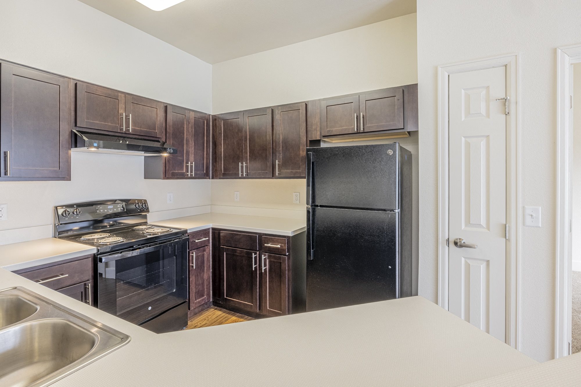 A kitchen with dark brown cabinets, stove, refrigerator