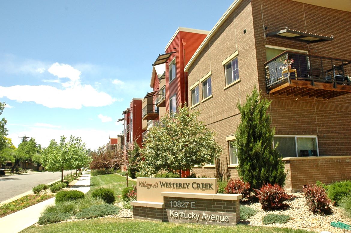 Exterior shot of VWC1, brown brick, orange siding, patios, landscaped with trees and grass