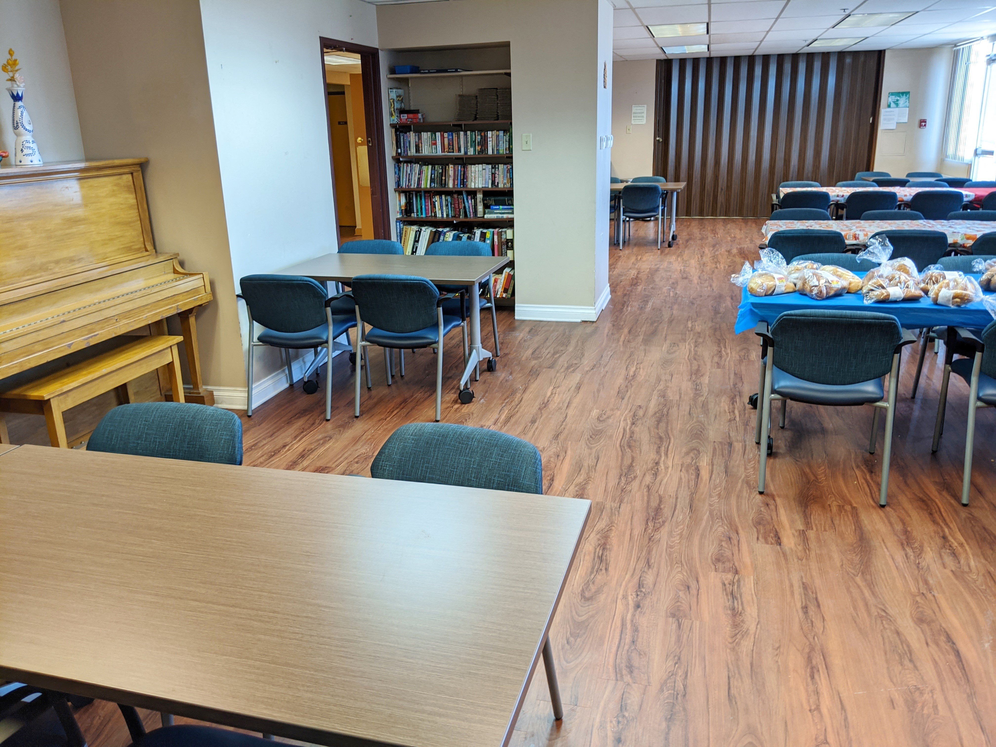Community room with tables and chairs, little library, and piano