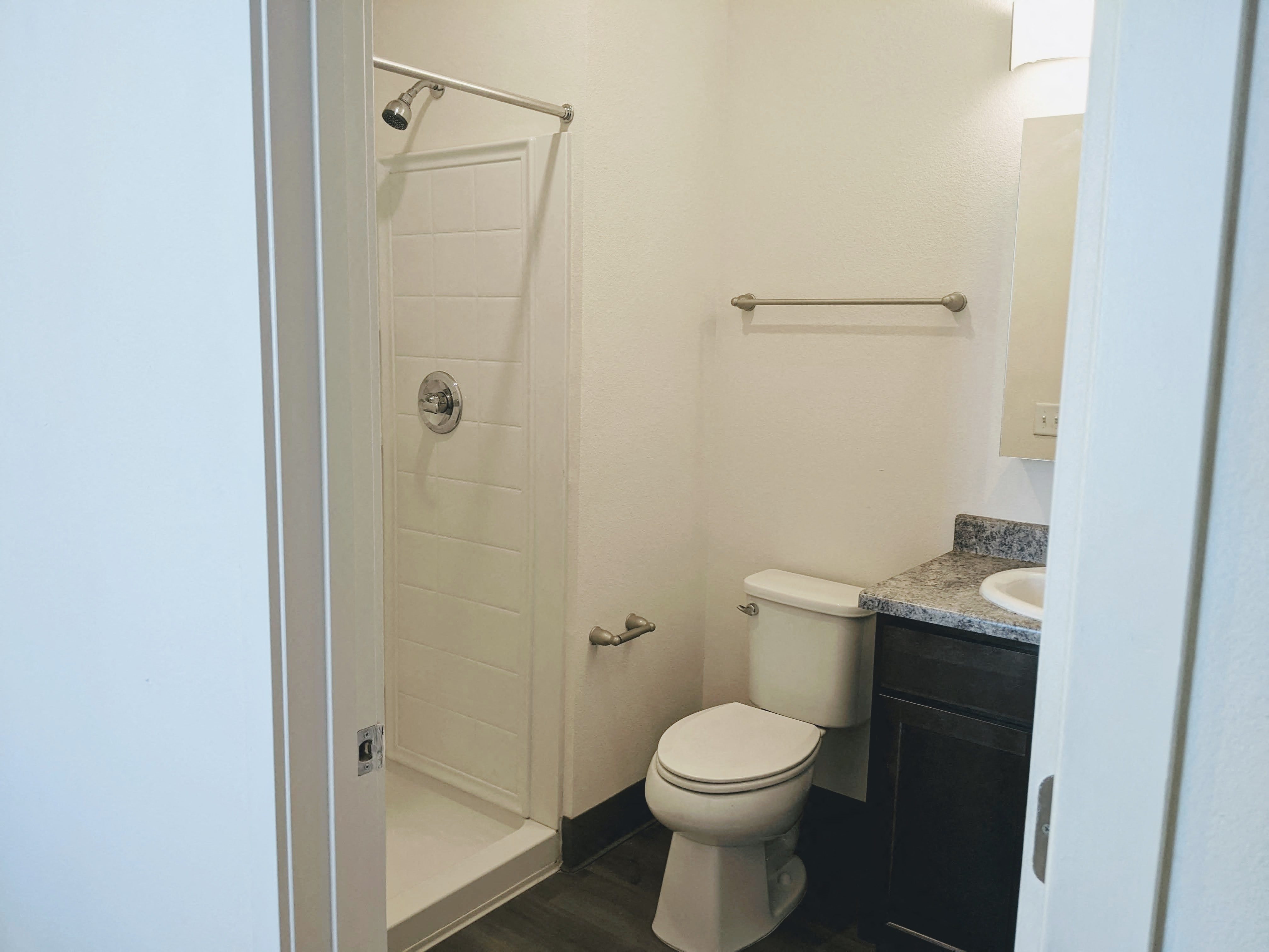 A bathroom with shower stall, toilet, and sink.