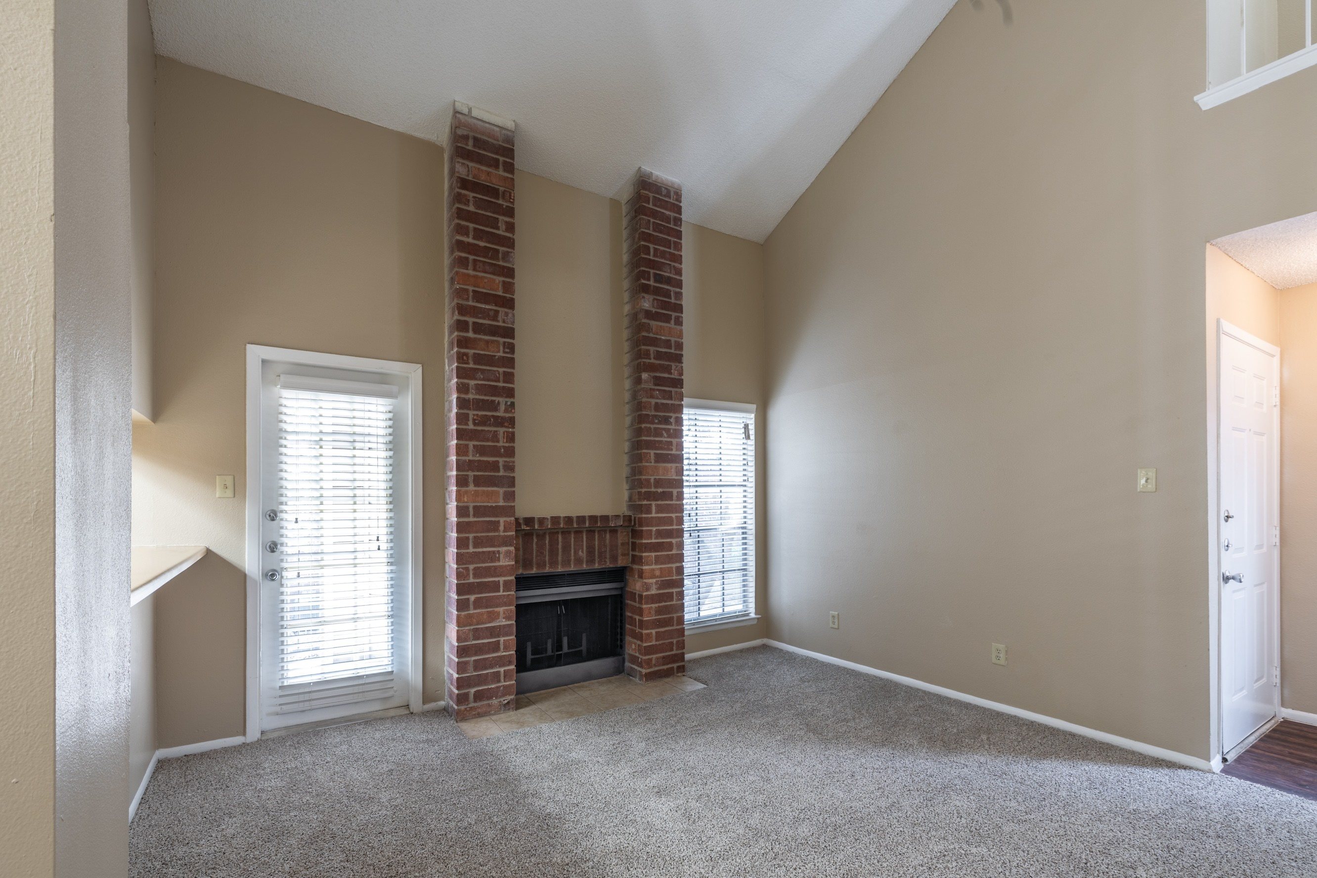 A room with a fireplace and two windows.