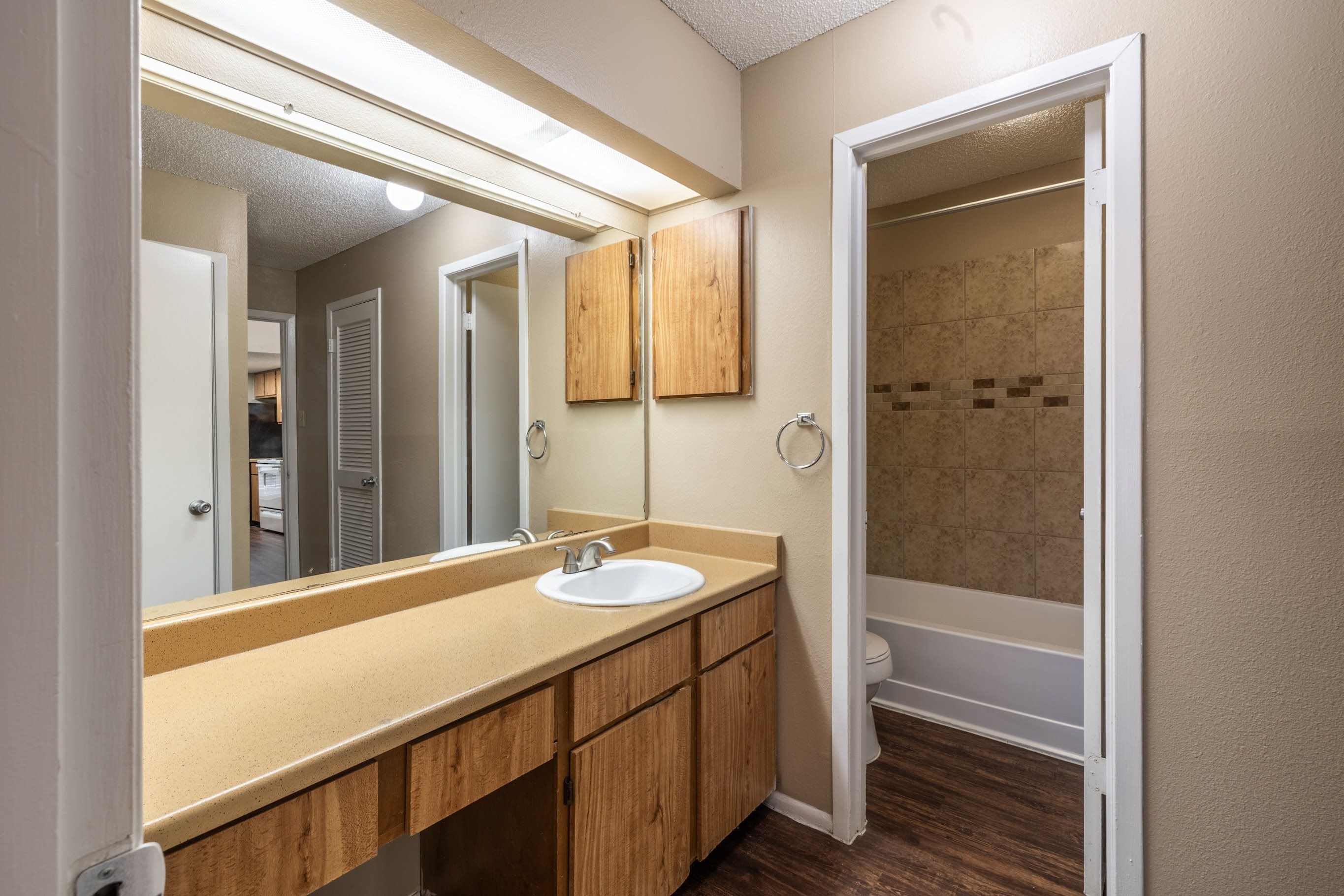 A bathroom with a sink, mirror, and wooden cabinets.