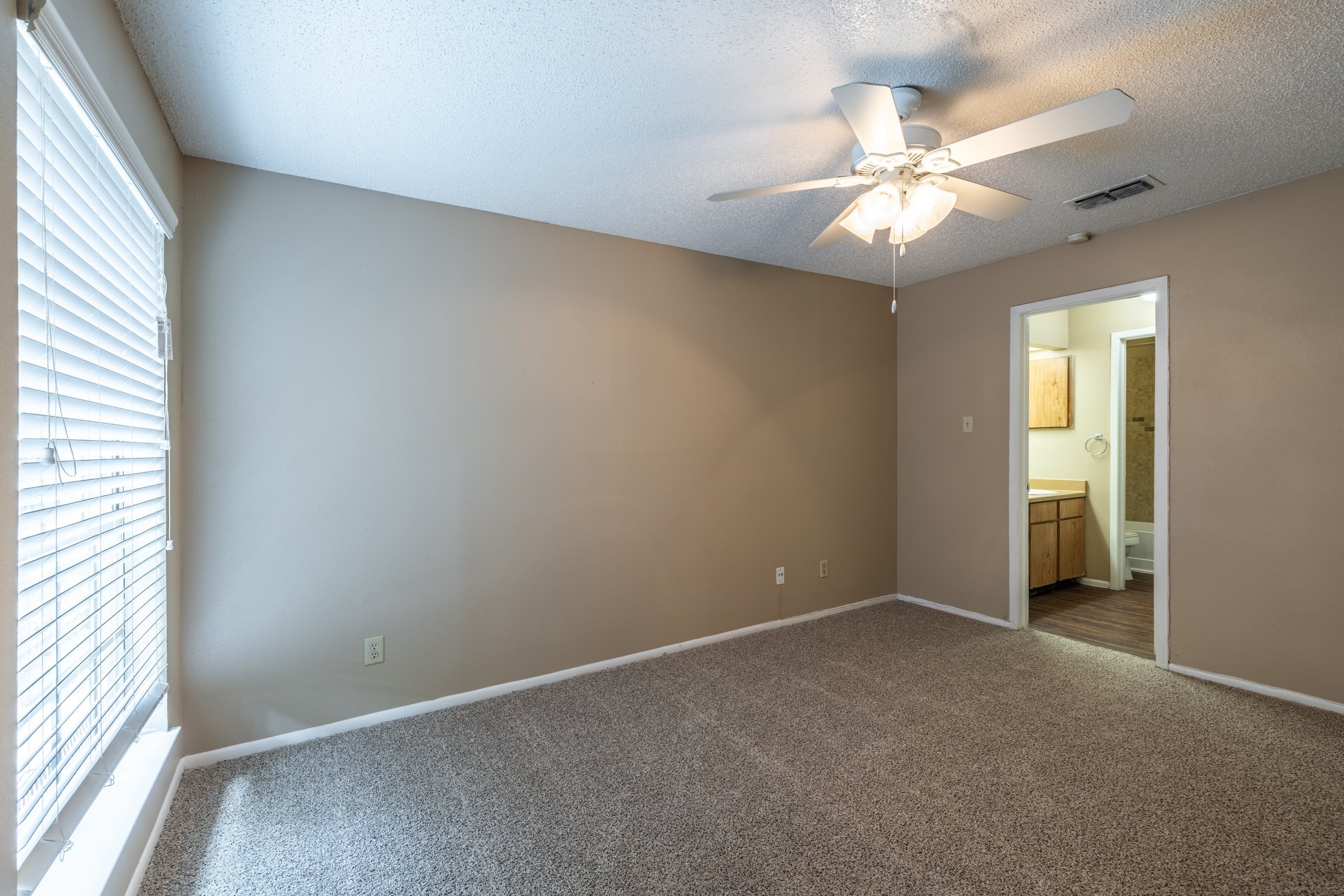 A room with a ceiling fan and carpeted floor.