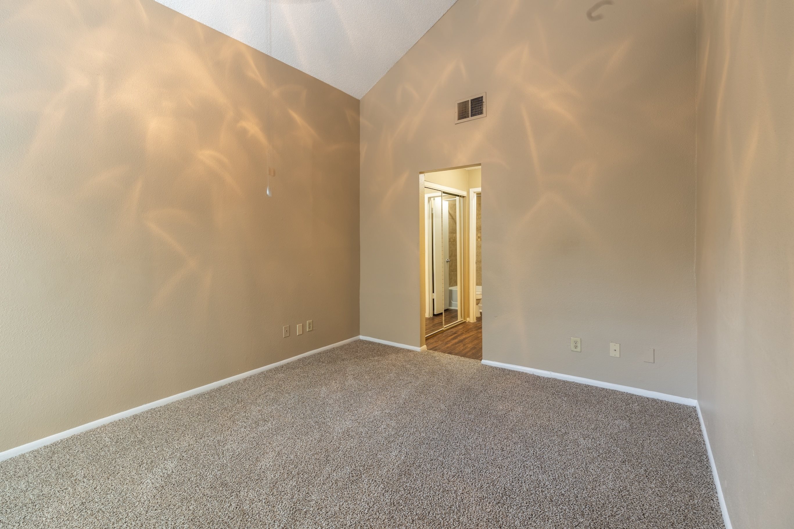 A room with a carpeted floor and a doorway leading to another room.
