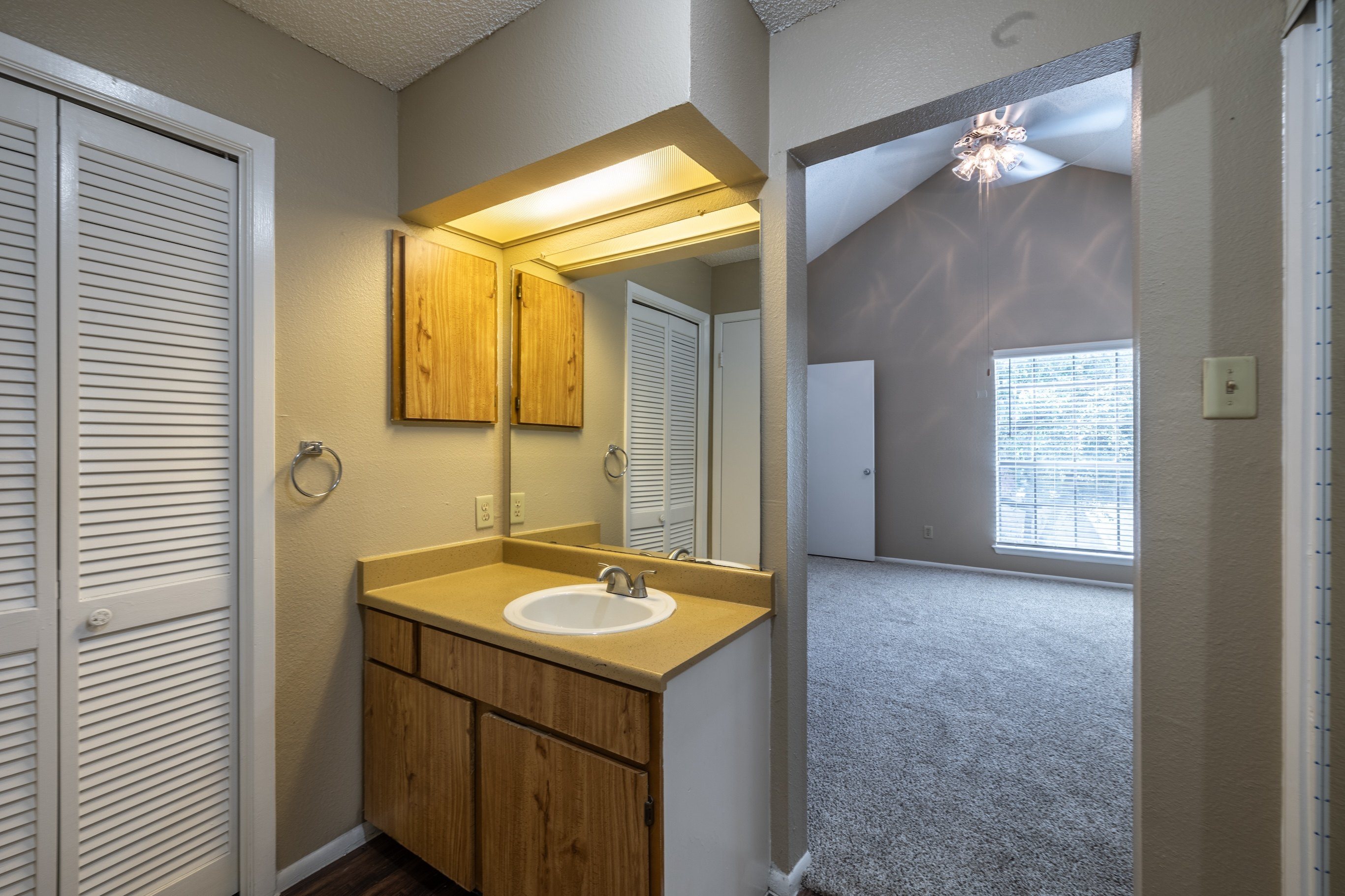 A bathroom with a sink, mirror, and wooden cabinets.