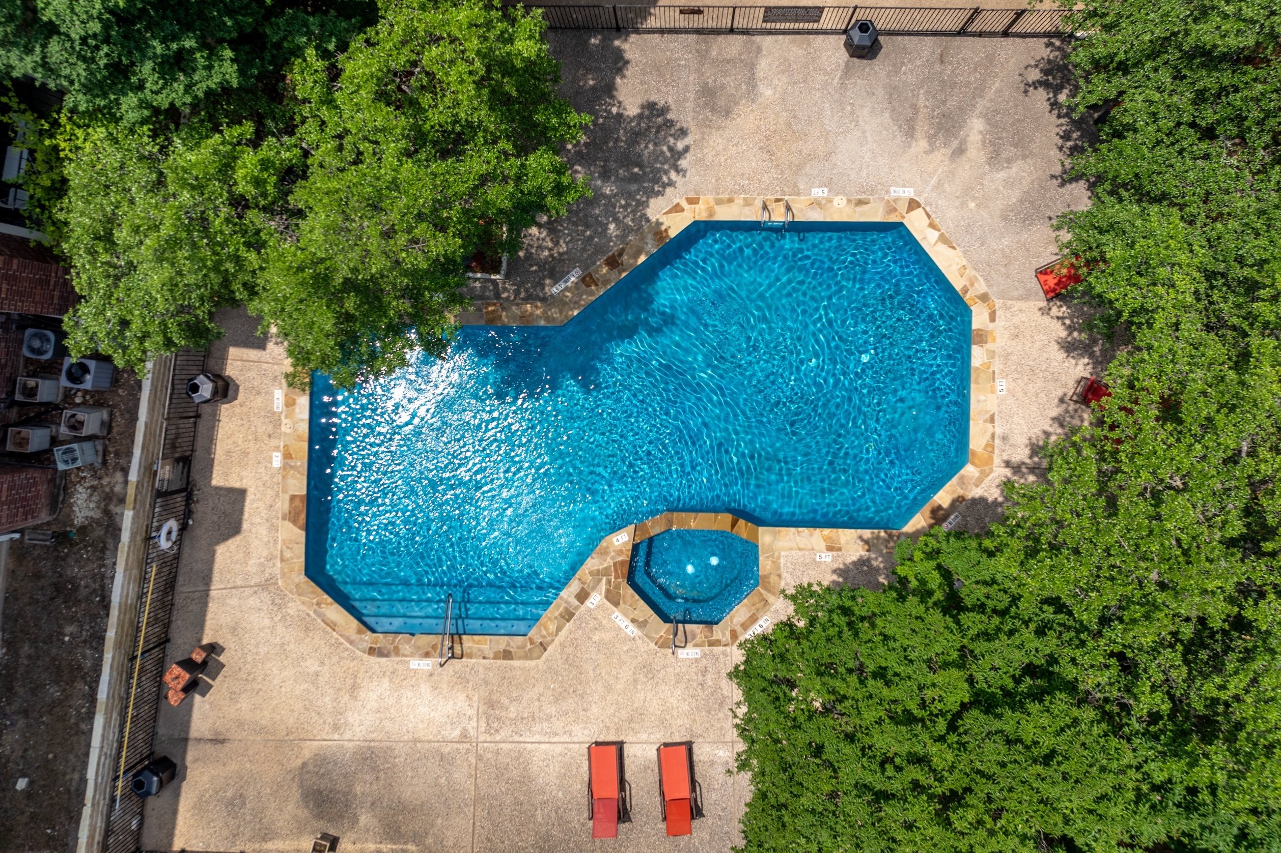 A small pool surrounded by trees and a concrete floor.