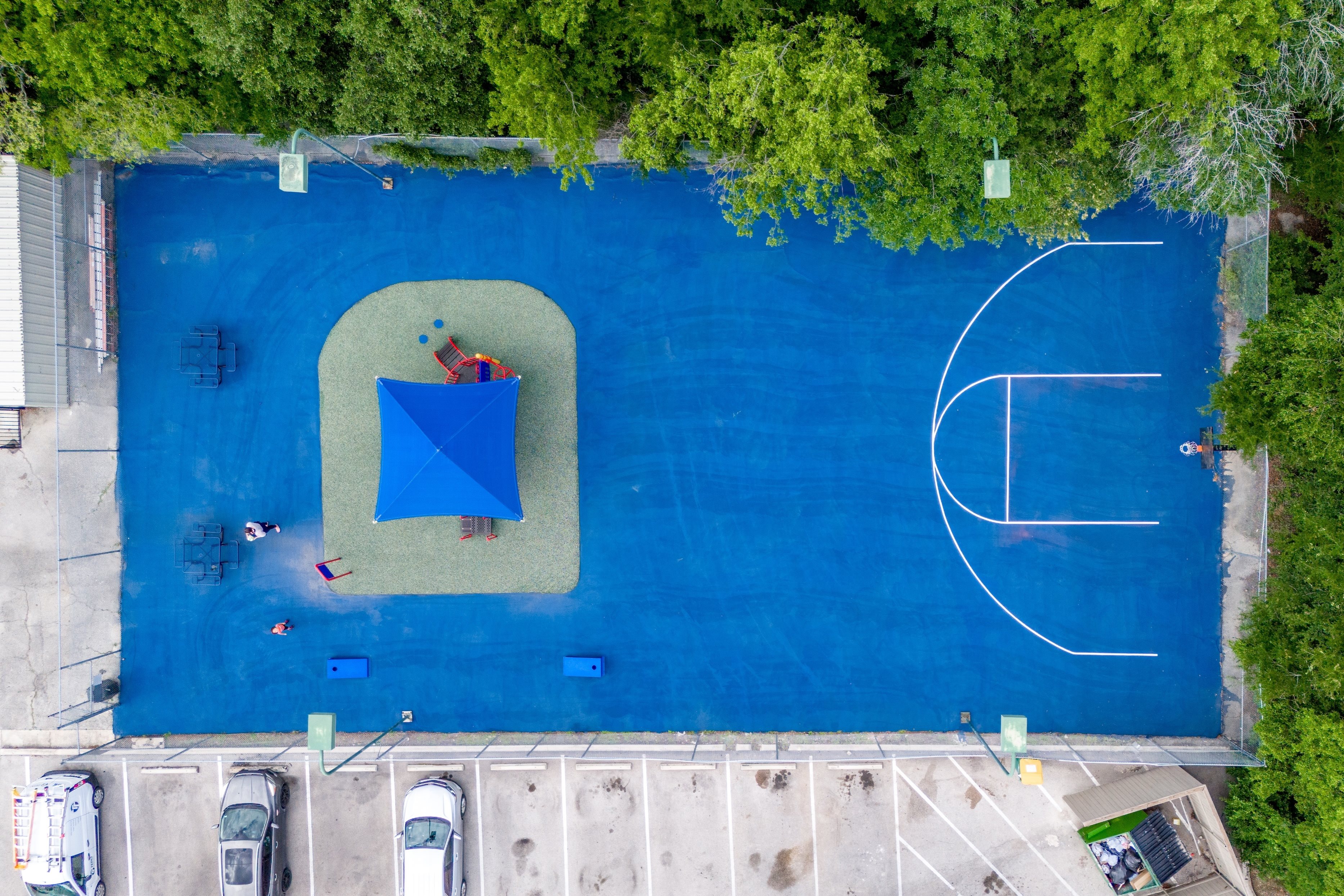 A blue rectangular pool with a basketball court in the middle.