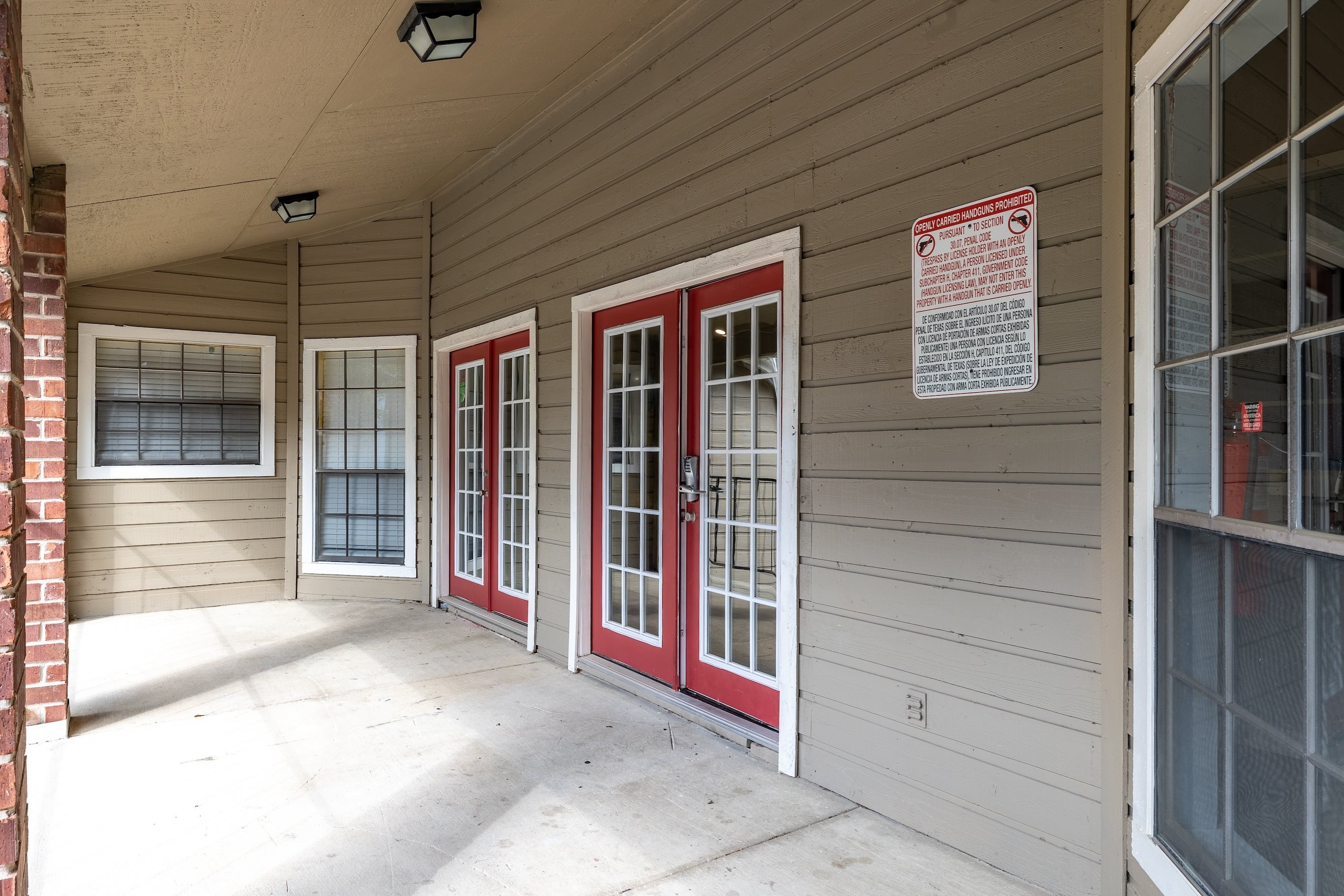 A porch with red doors and a sign on the wall.