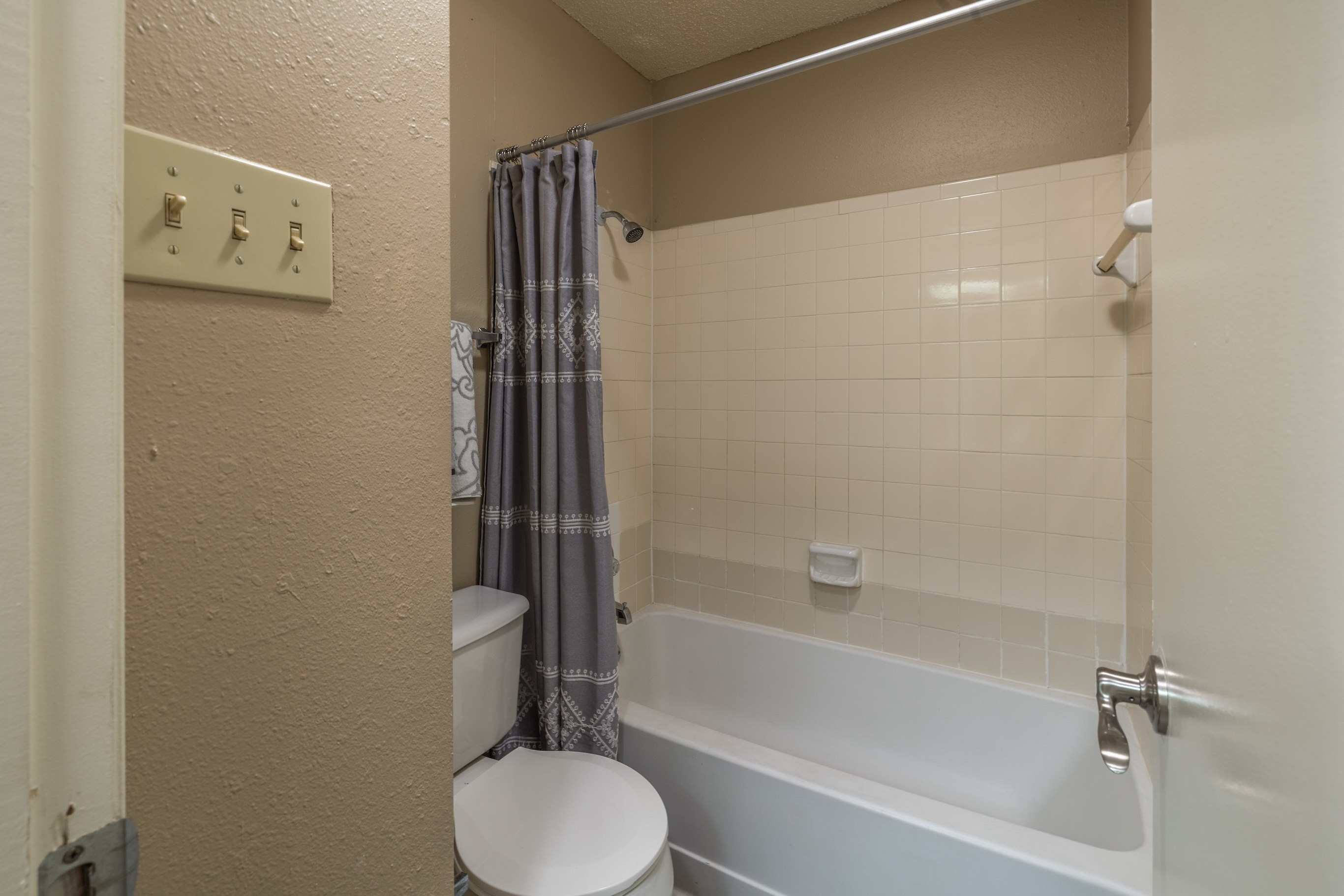 A white toilet sits next to a bathtub in a bathroom.