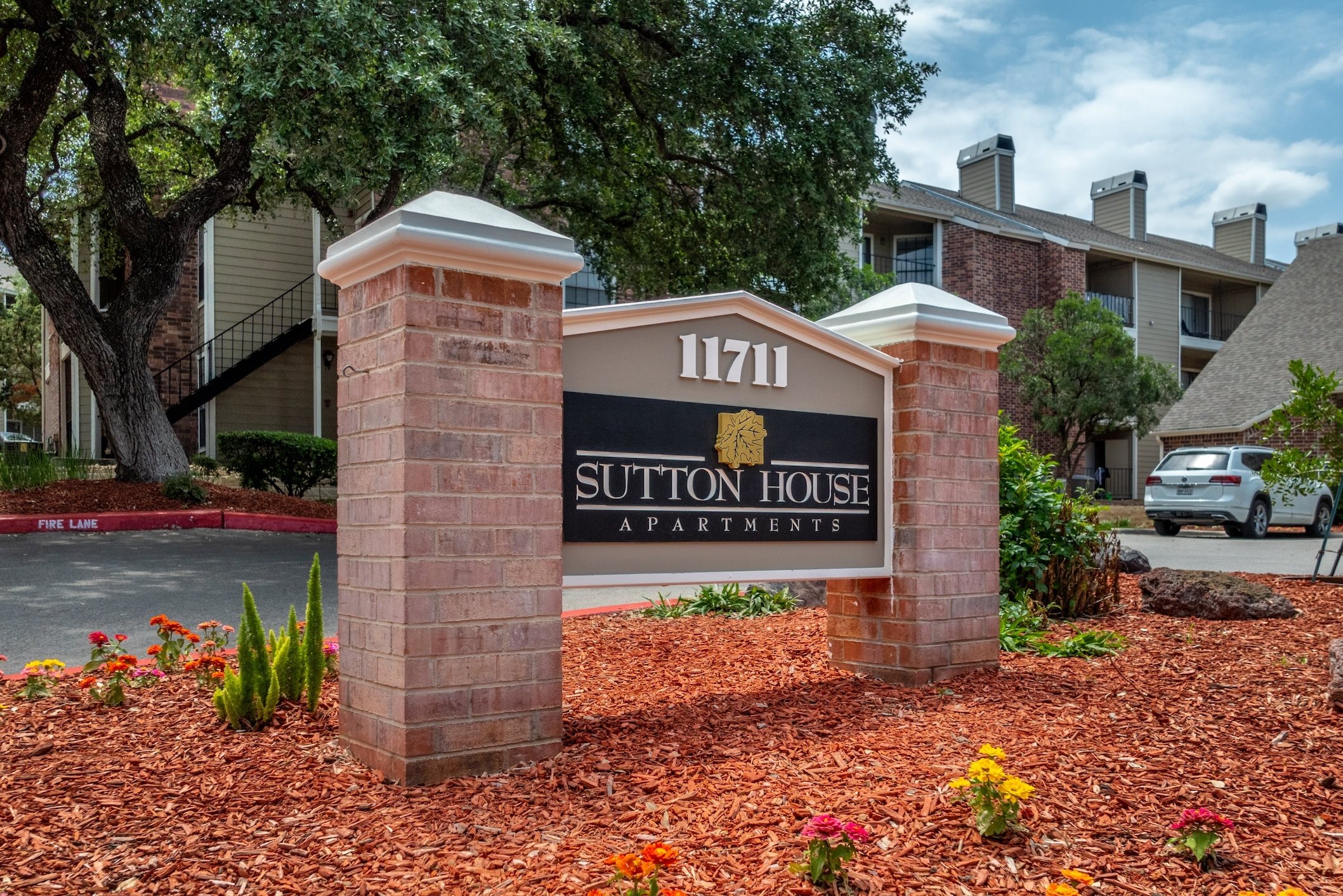 A brick pillar with a sign that says Sutton House Apartment.