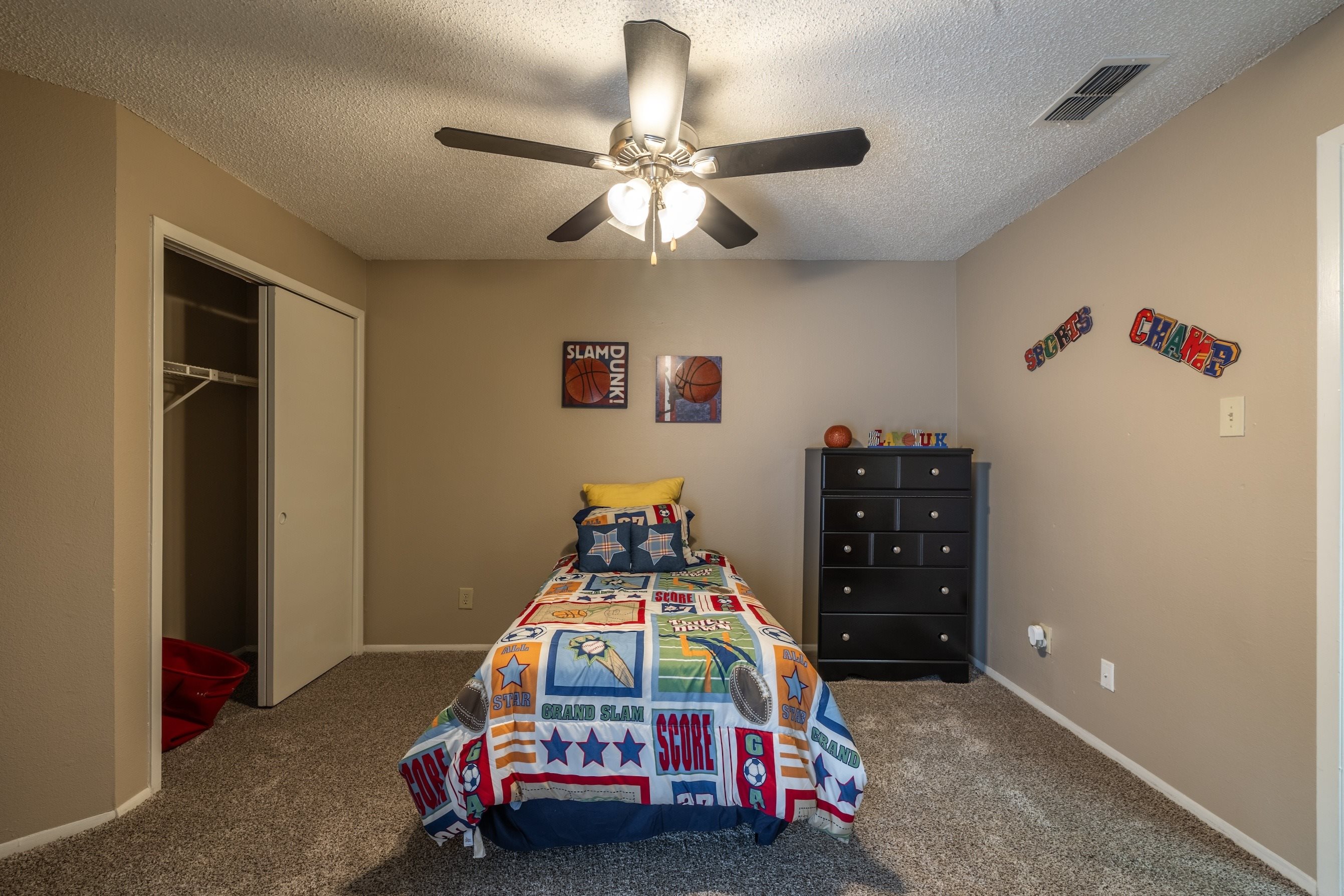 A bedroom with a bed, dresser, and ceiling fan.