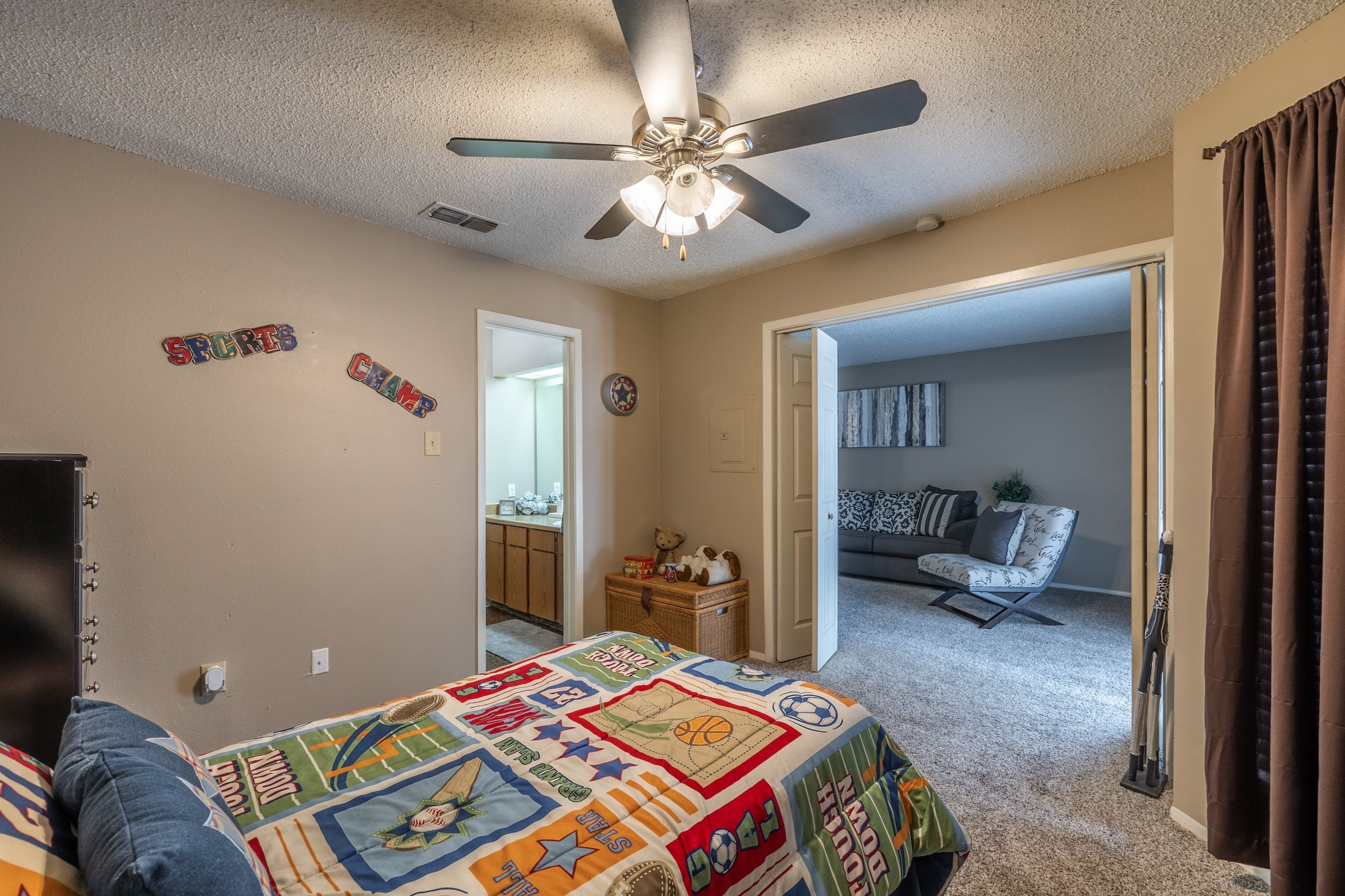 A bedroom with a bed, a ceiling fan, and a chair.