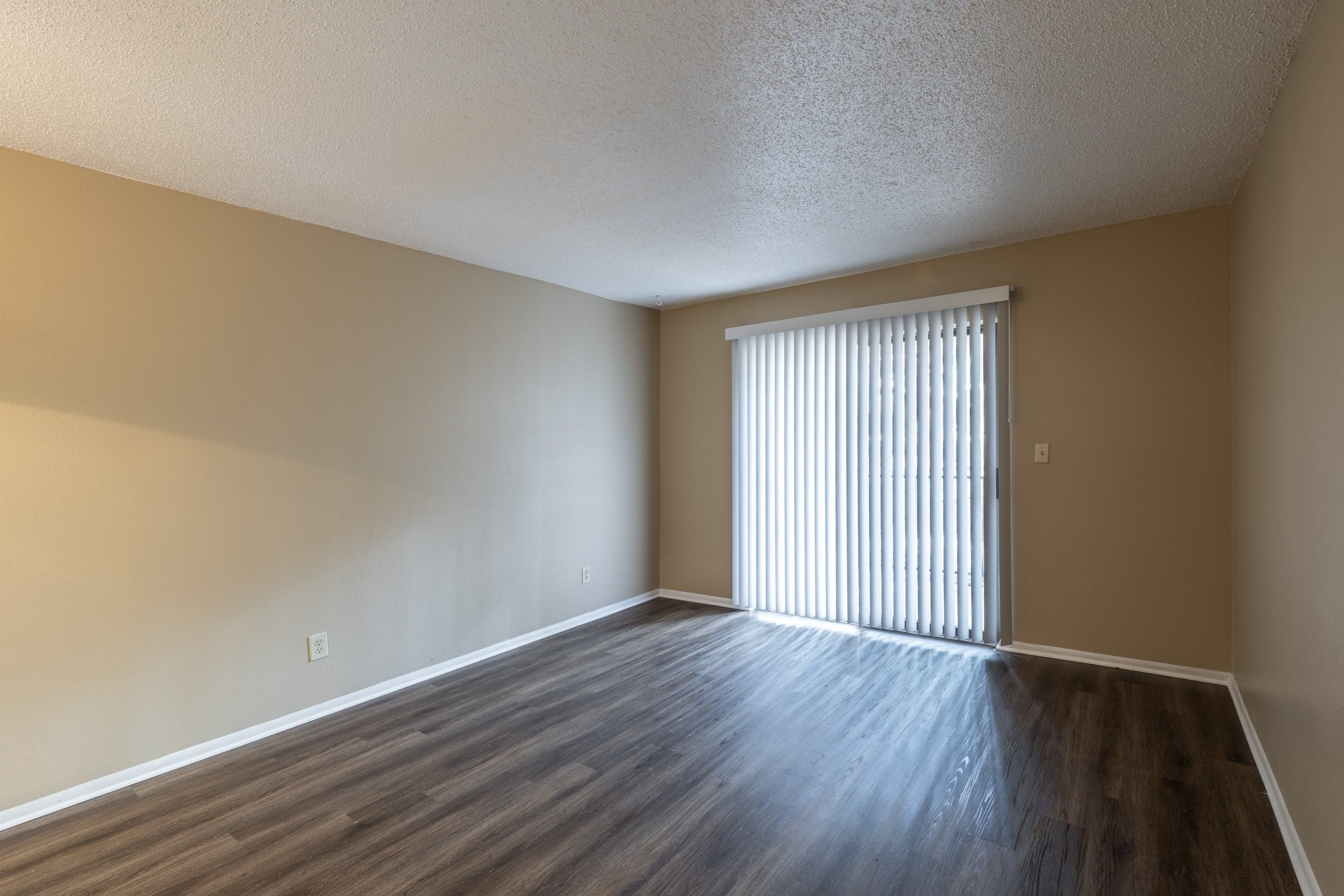 A room with wooden floors and a window with blinds.