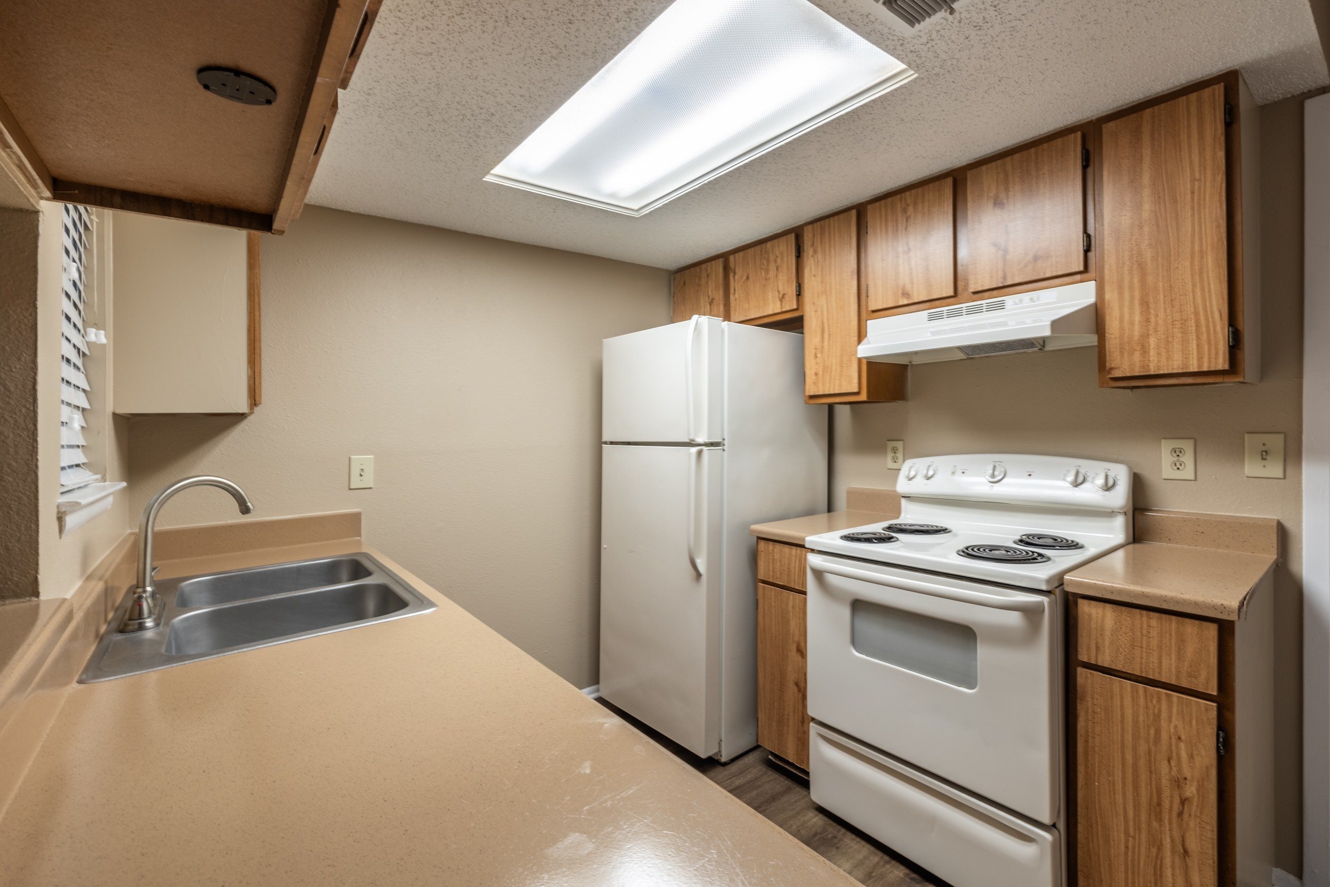 A kitchen with a stove, sink, and refrigerator.