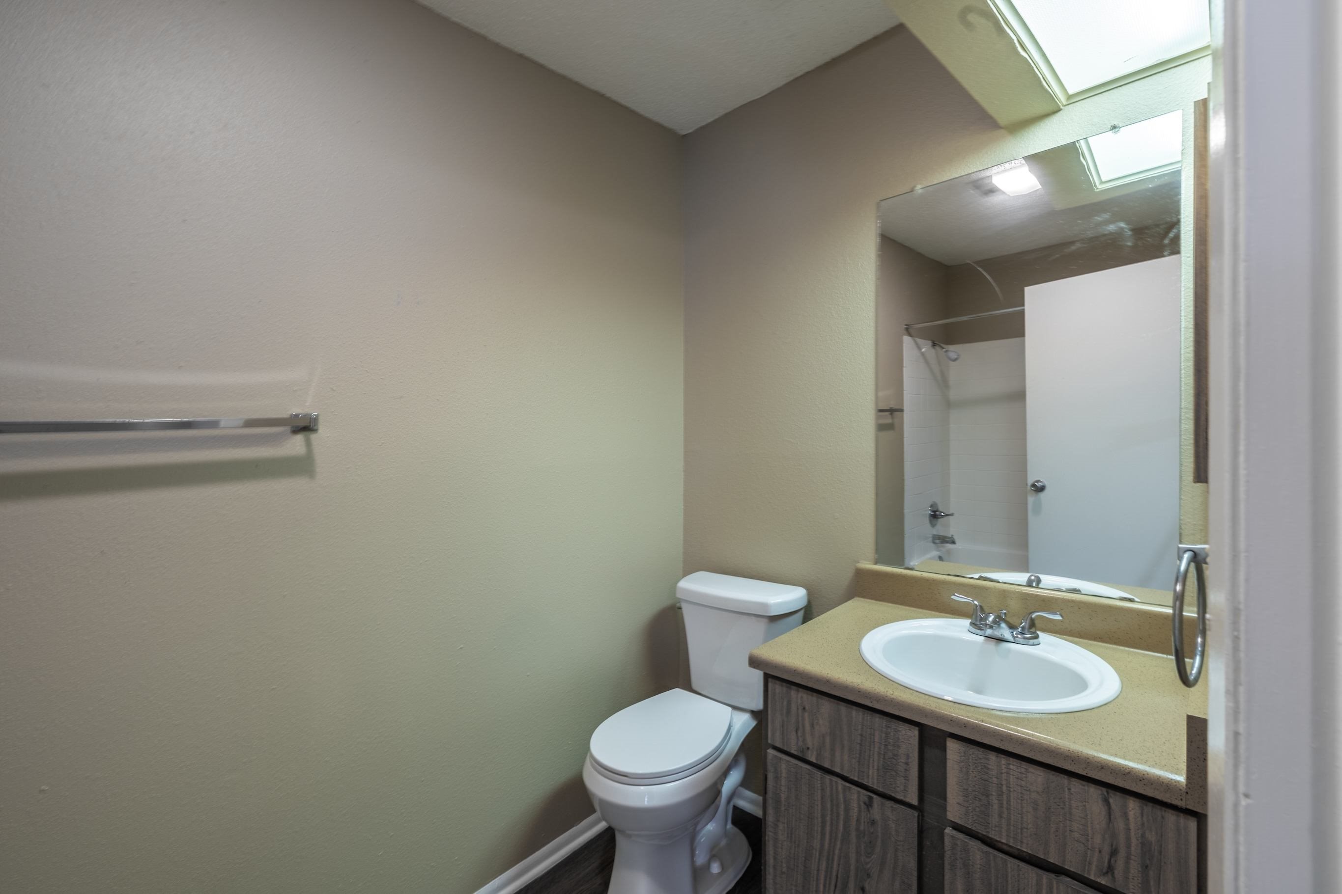 A bathroom with a toilet, sink, and mirror.