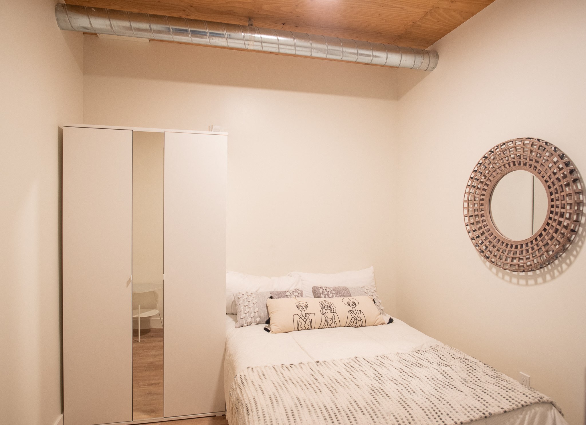a small bedroom with a bed and a mirror
