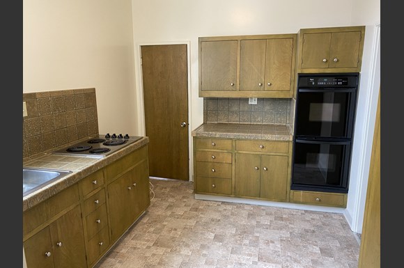 a kitchen with wooden cabinets and a black oven and sink