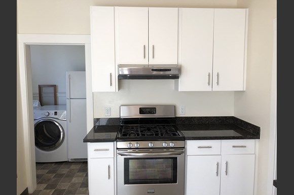 a kitchen with white cabinets and stainless steel appliances and a washing machine