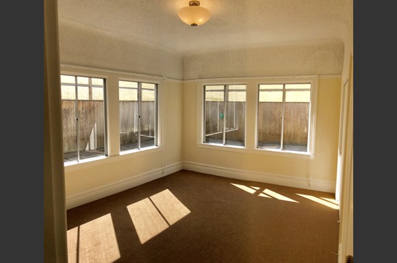 an empty living room with three windows and a carpet