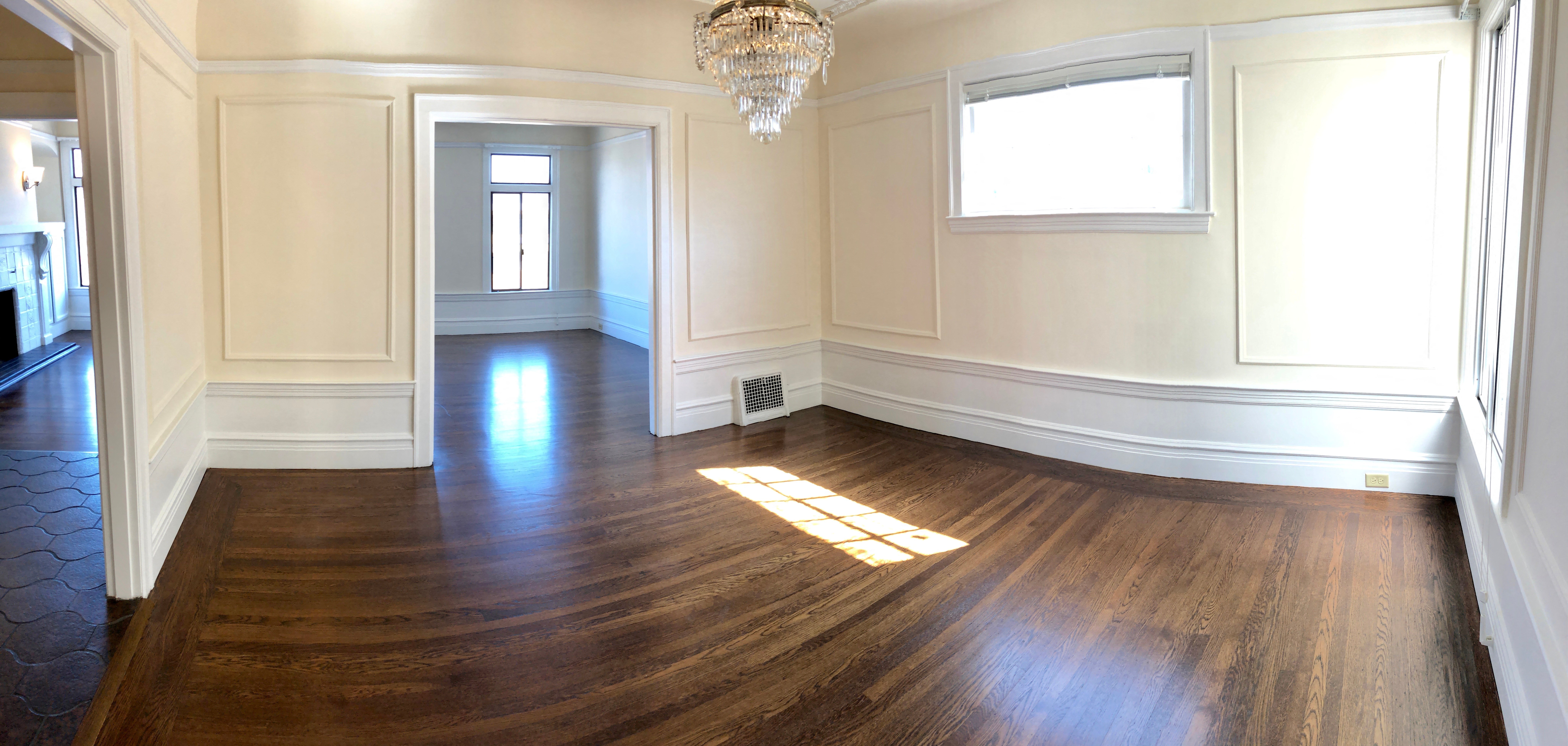 an empty living room with wood floors and a chandelier