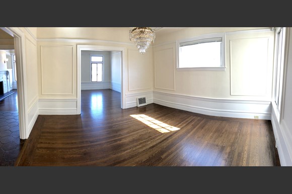 an empty living room with wood floors and a chandelier