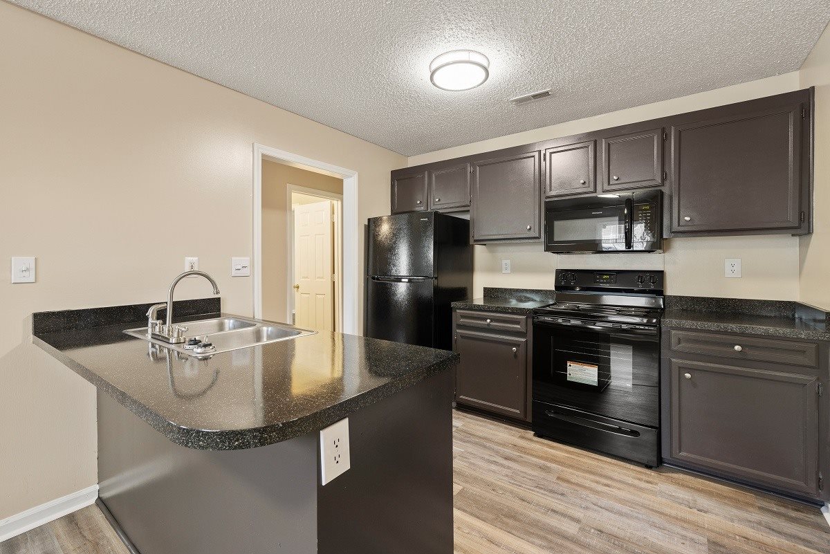 A kitchen with black appliances and a granite countertop.