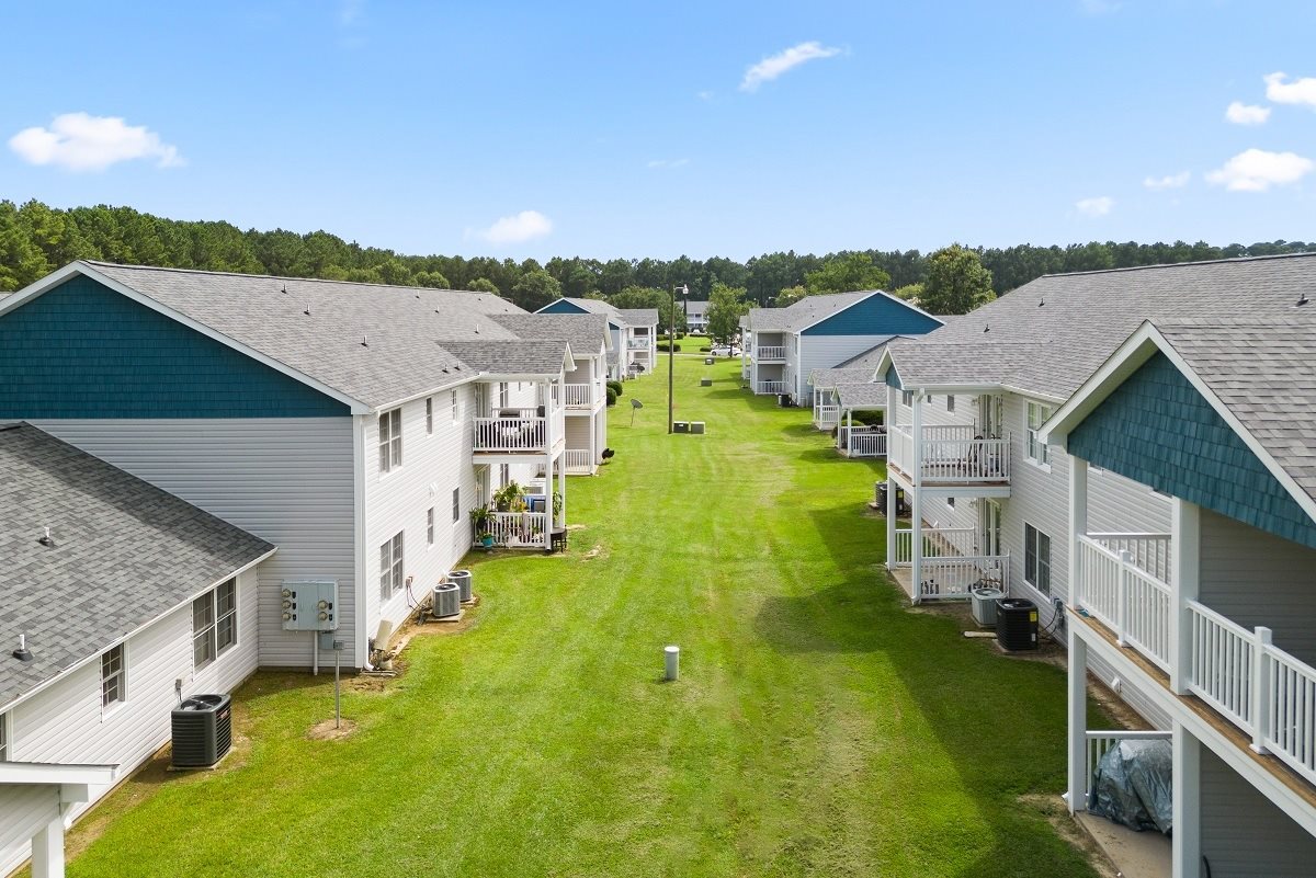 A view of a grassy area between two rows of houses.