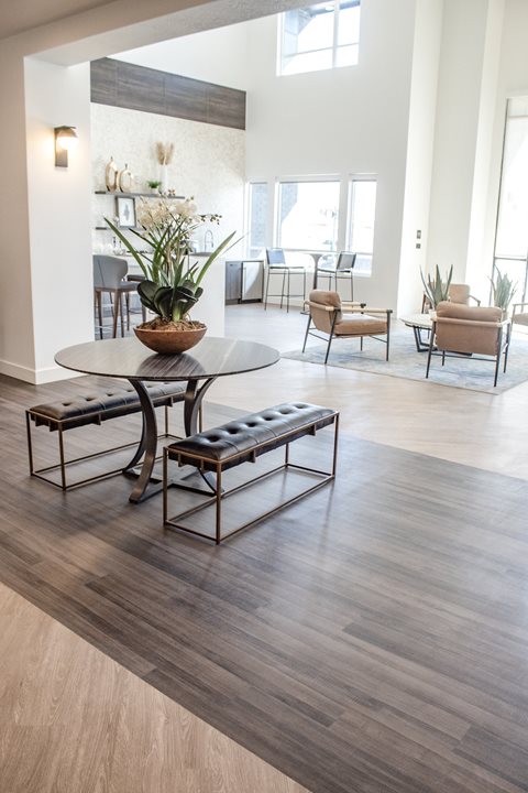 A living room with a wooden floor and a round table with a plant on top of it