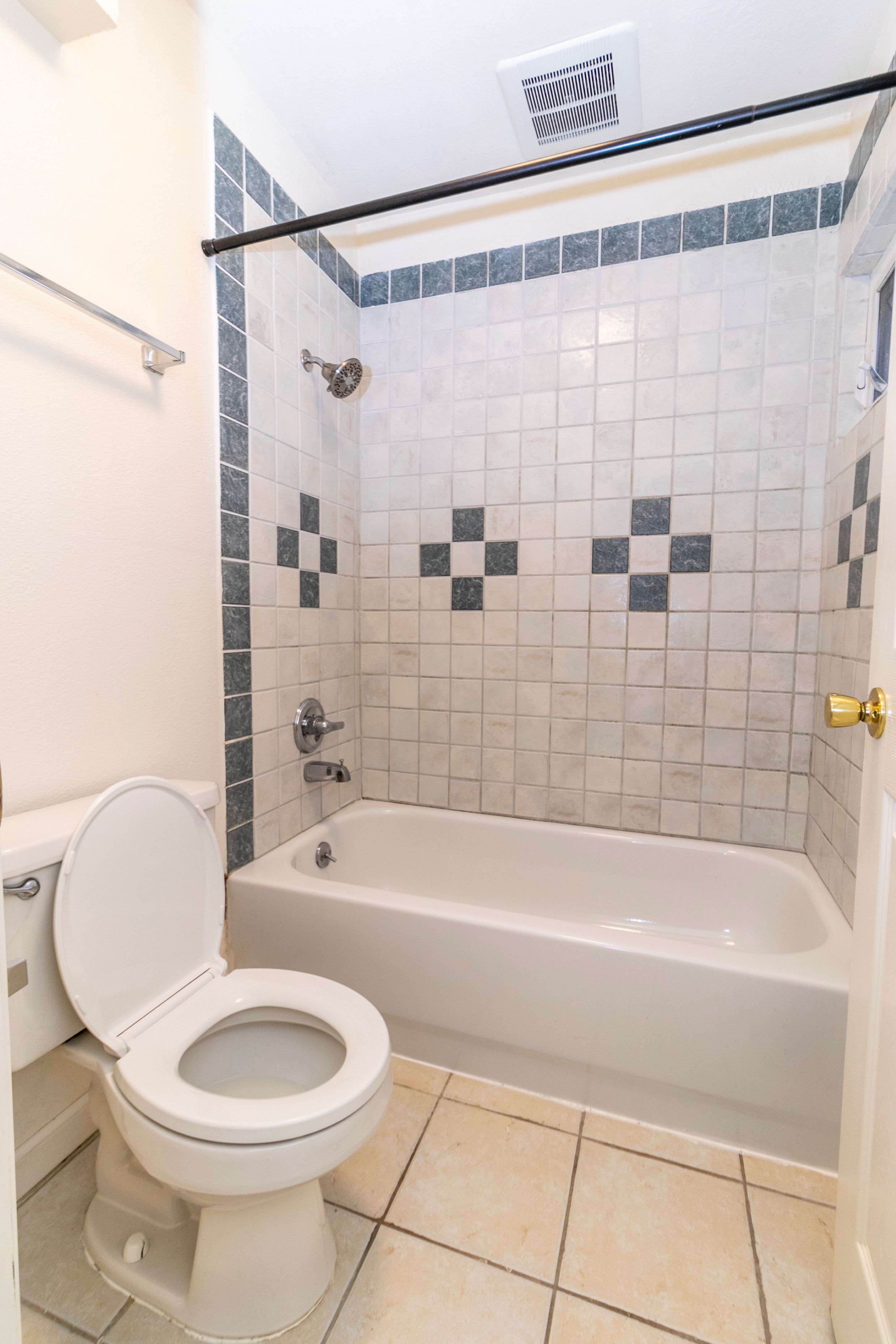 A white toilet is in a bathroom with a white bathtub and a black and white tile shower.