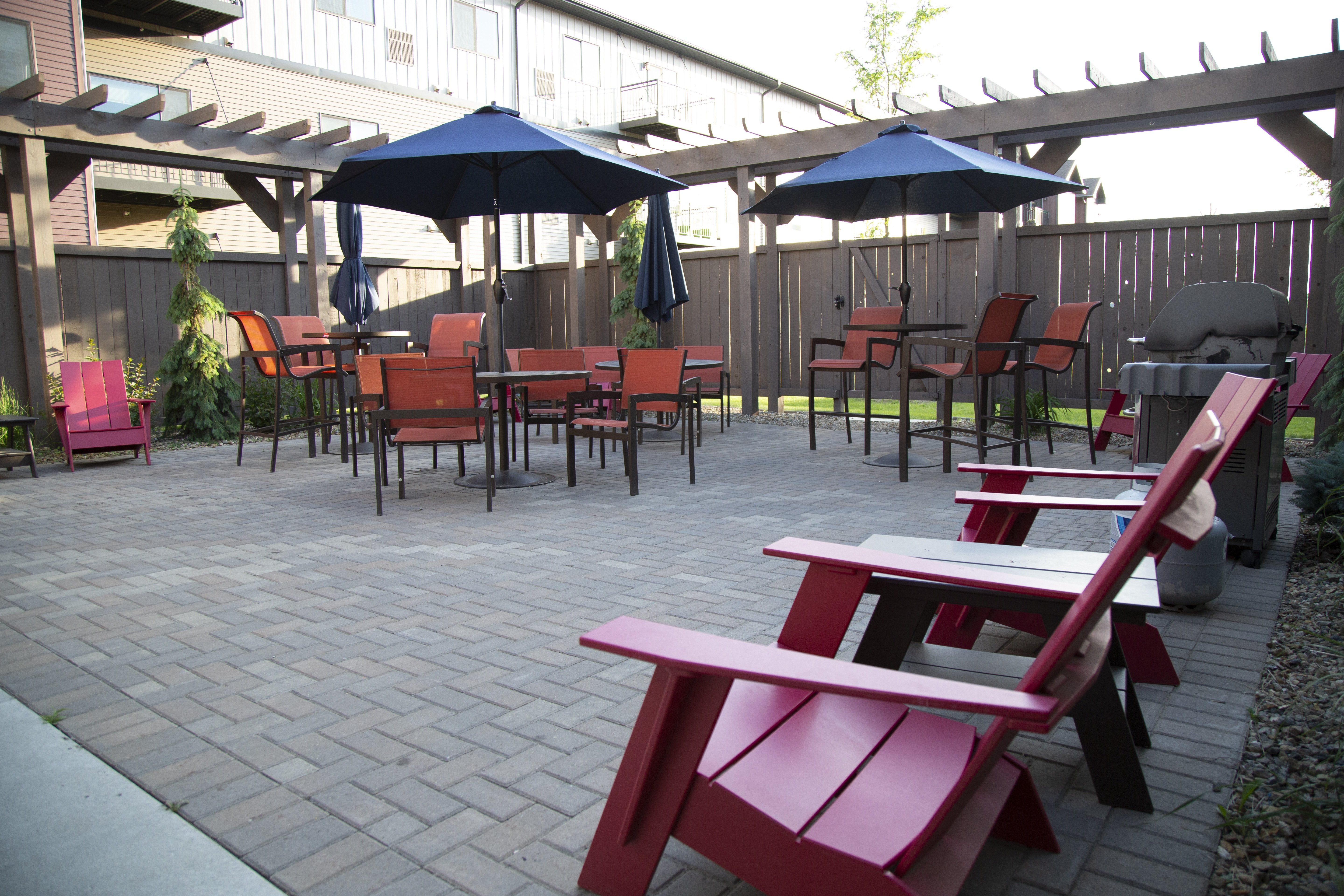 A patio with red chairs and tables.