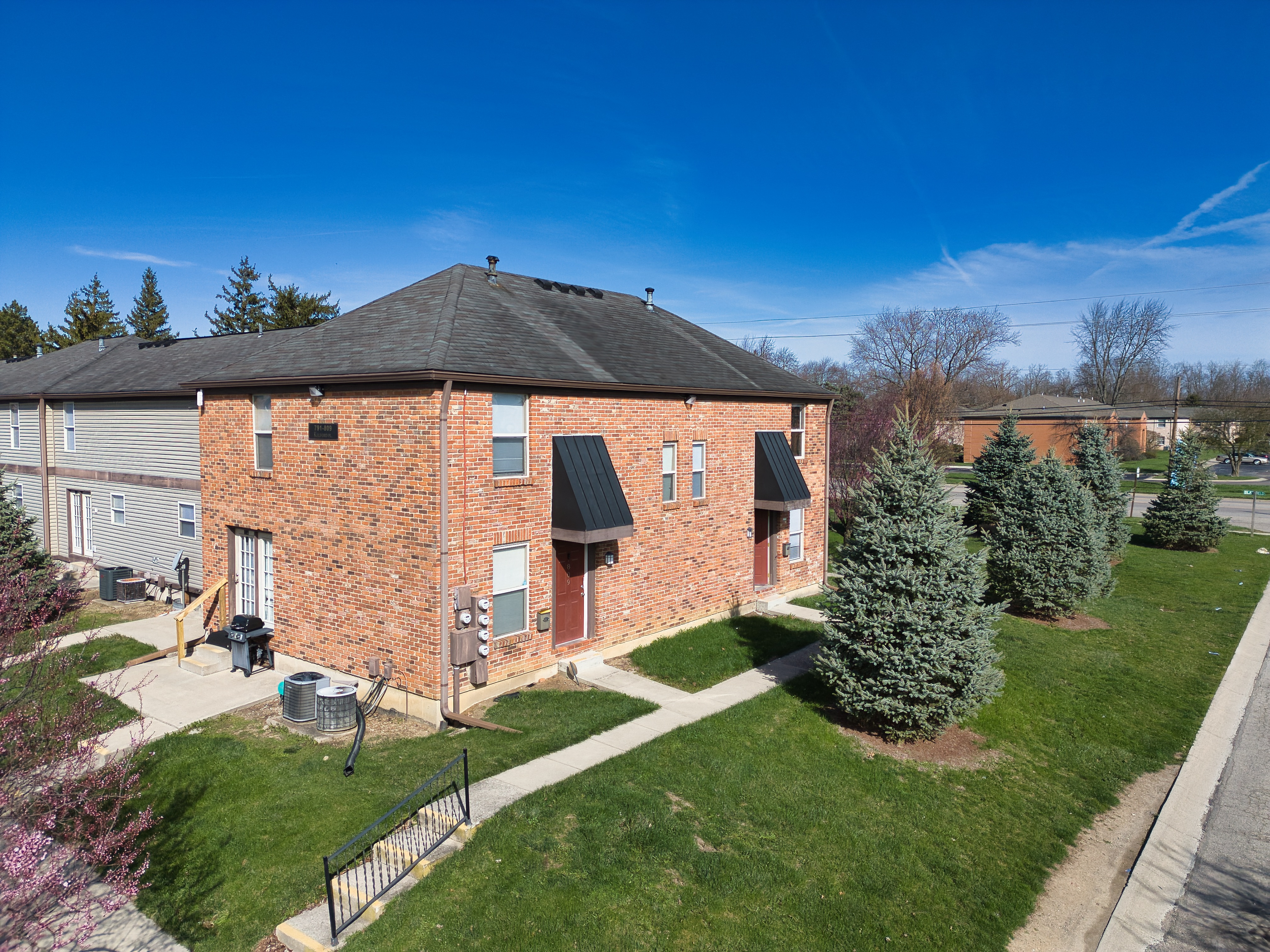 a brick building with a black roof and a green lawn and trees