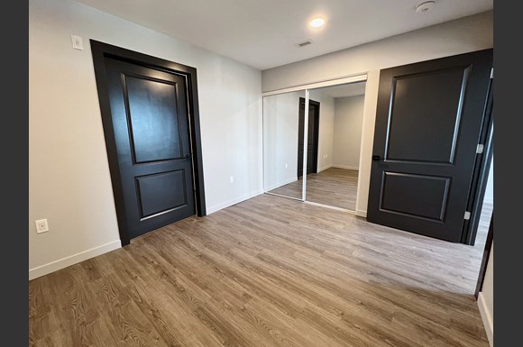 Bedroom with hardwood floors and mirrored closet doors