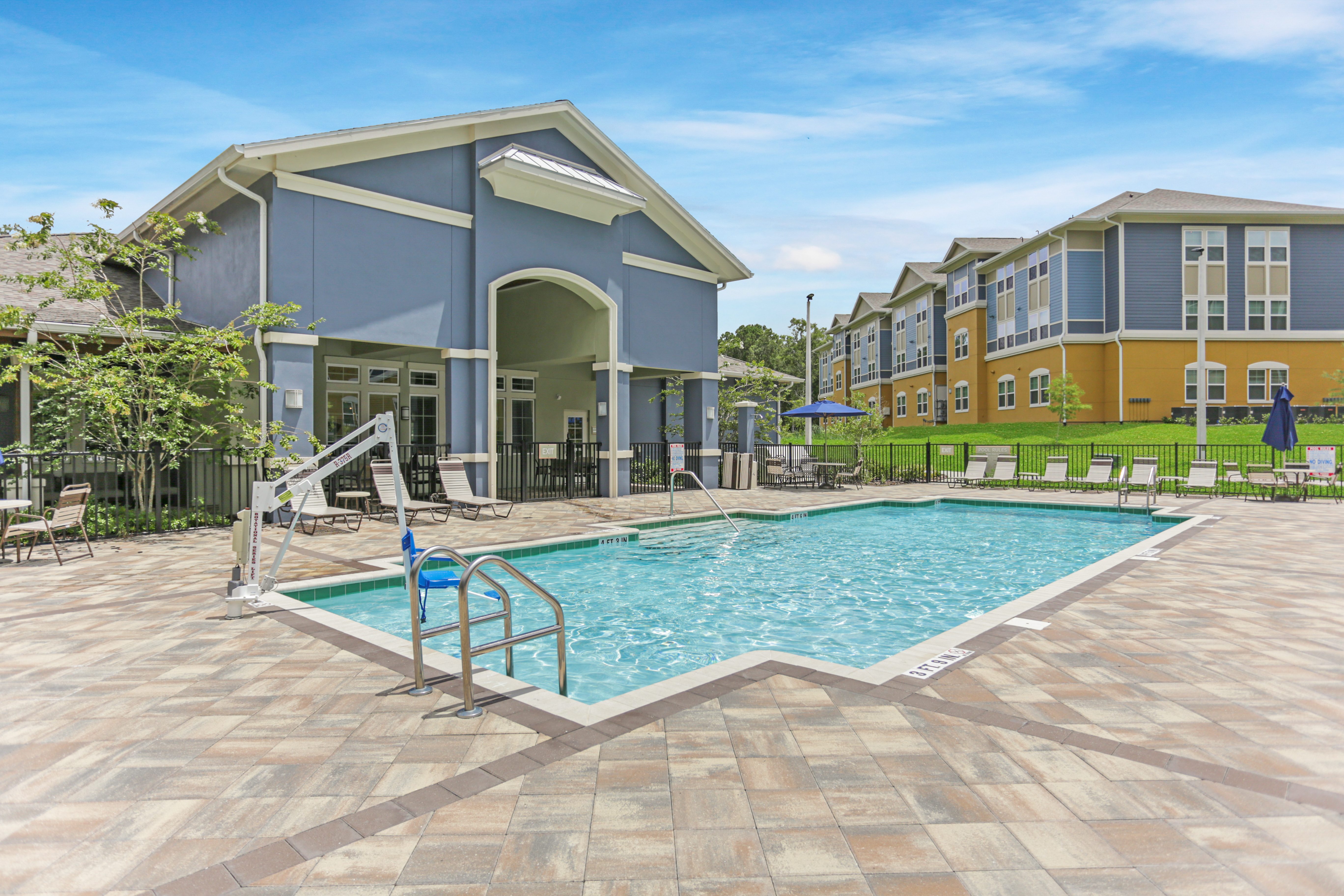 A swimming pool in front of a building with a blue sky in the background.