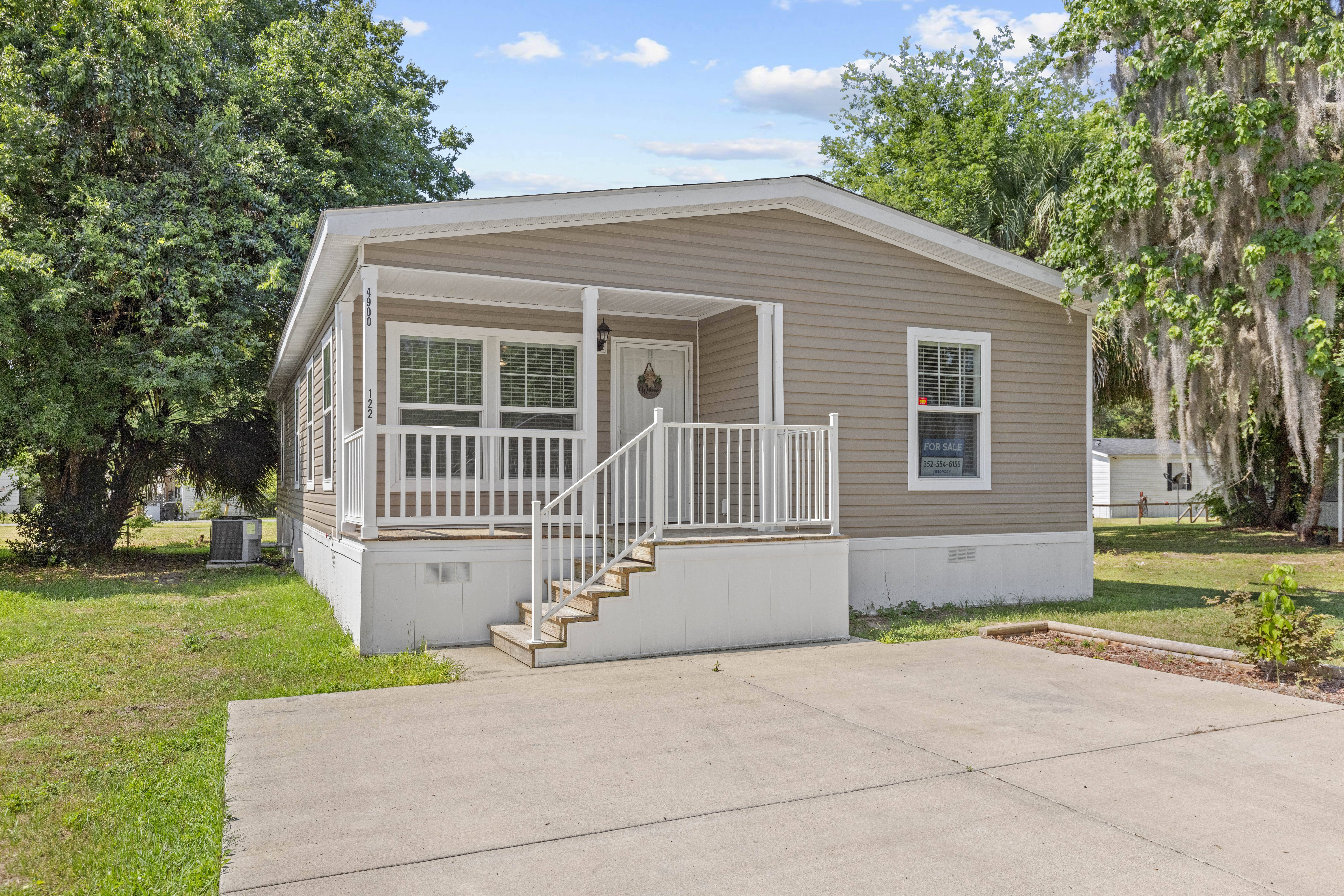 A small house with a porch and a staircase leading to the front door.,A small house with a porch and a staircase leading to the front door.