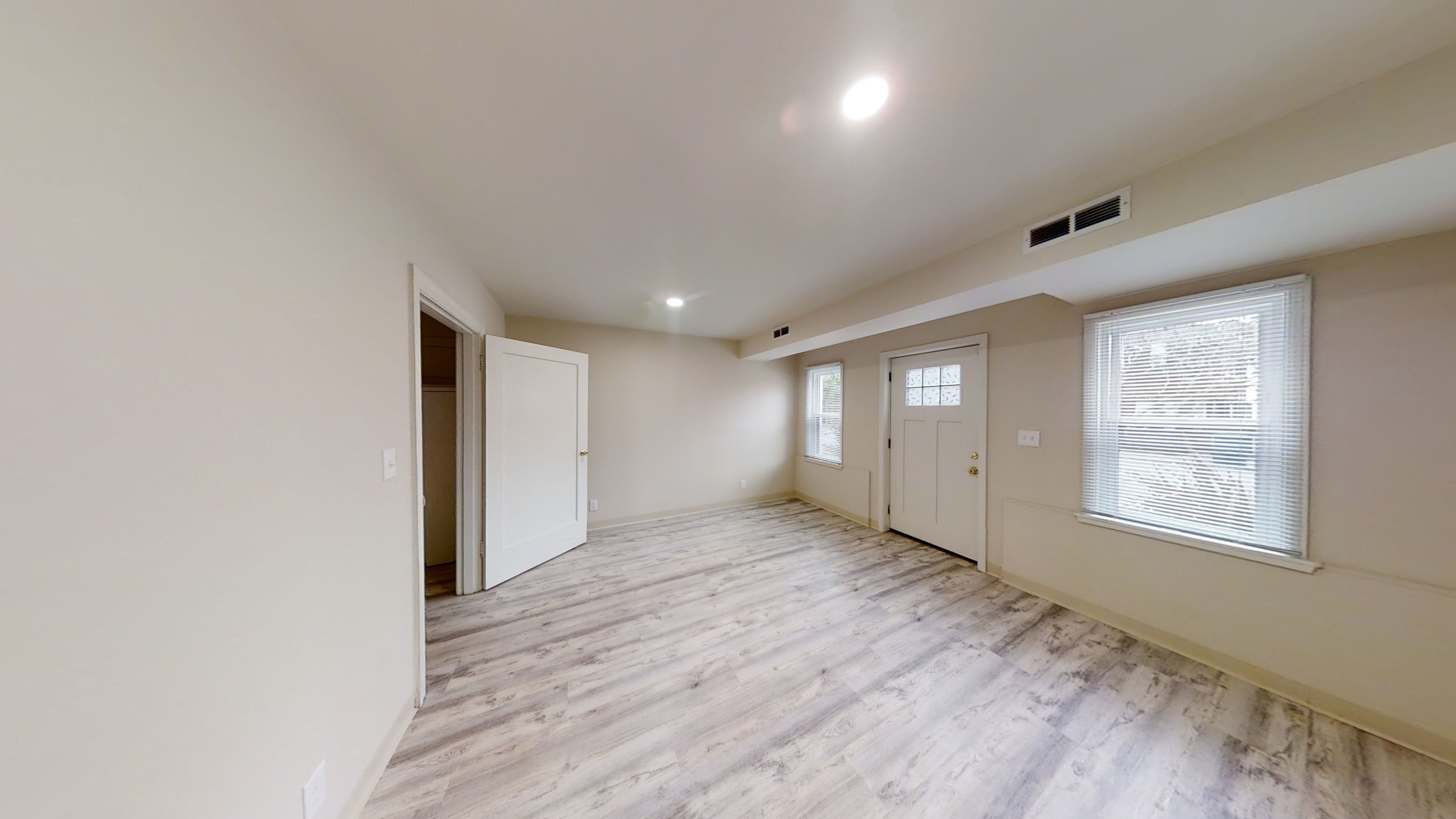A spacious room with wooden flooring and white walls.