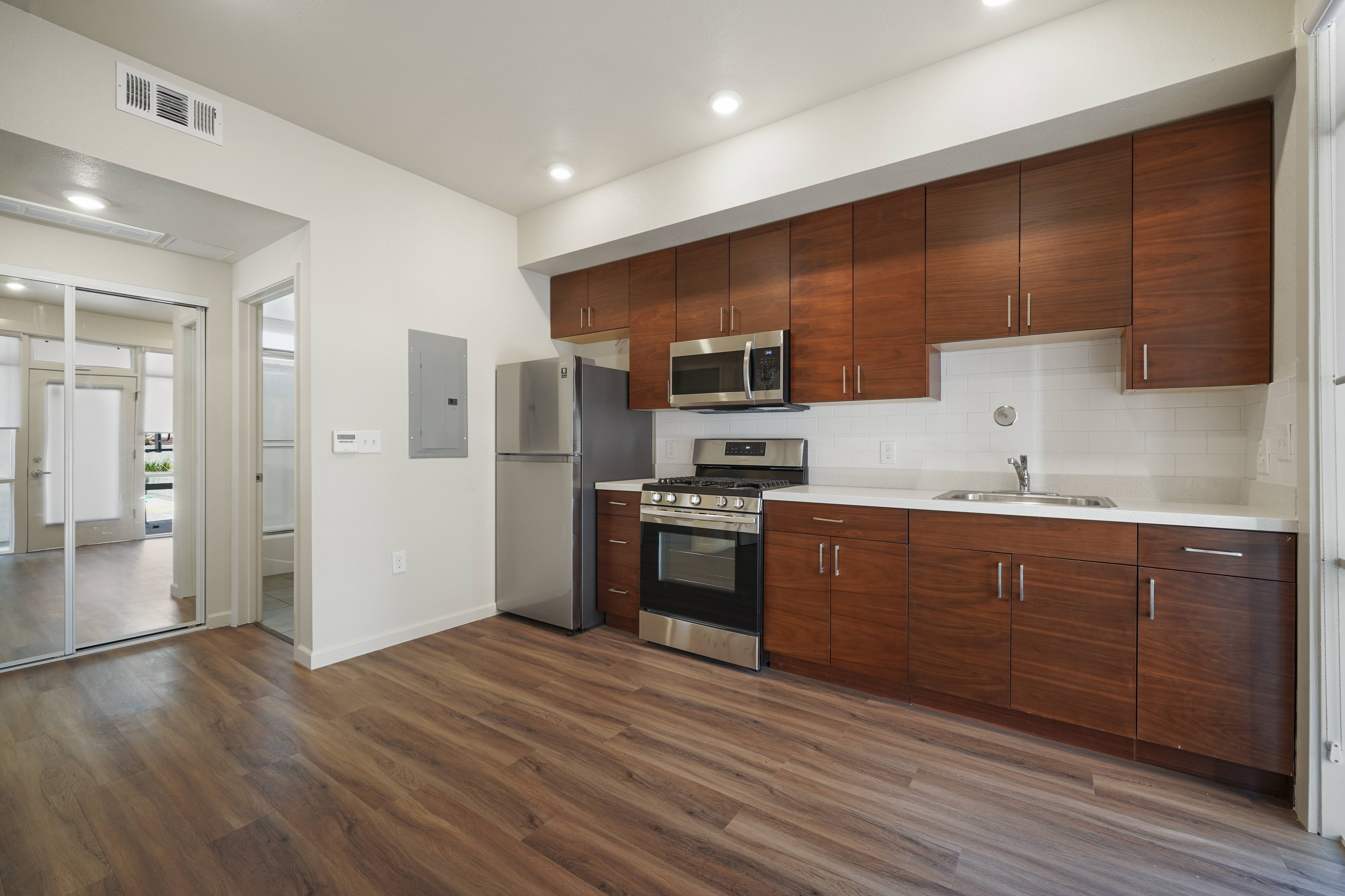 A kitchen with wooden cabinets and a stainless steel refrigerator.