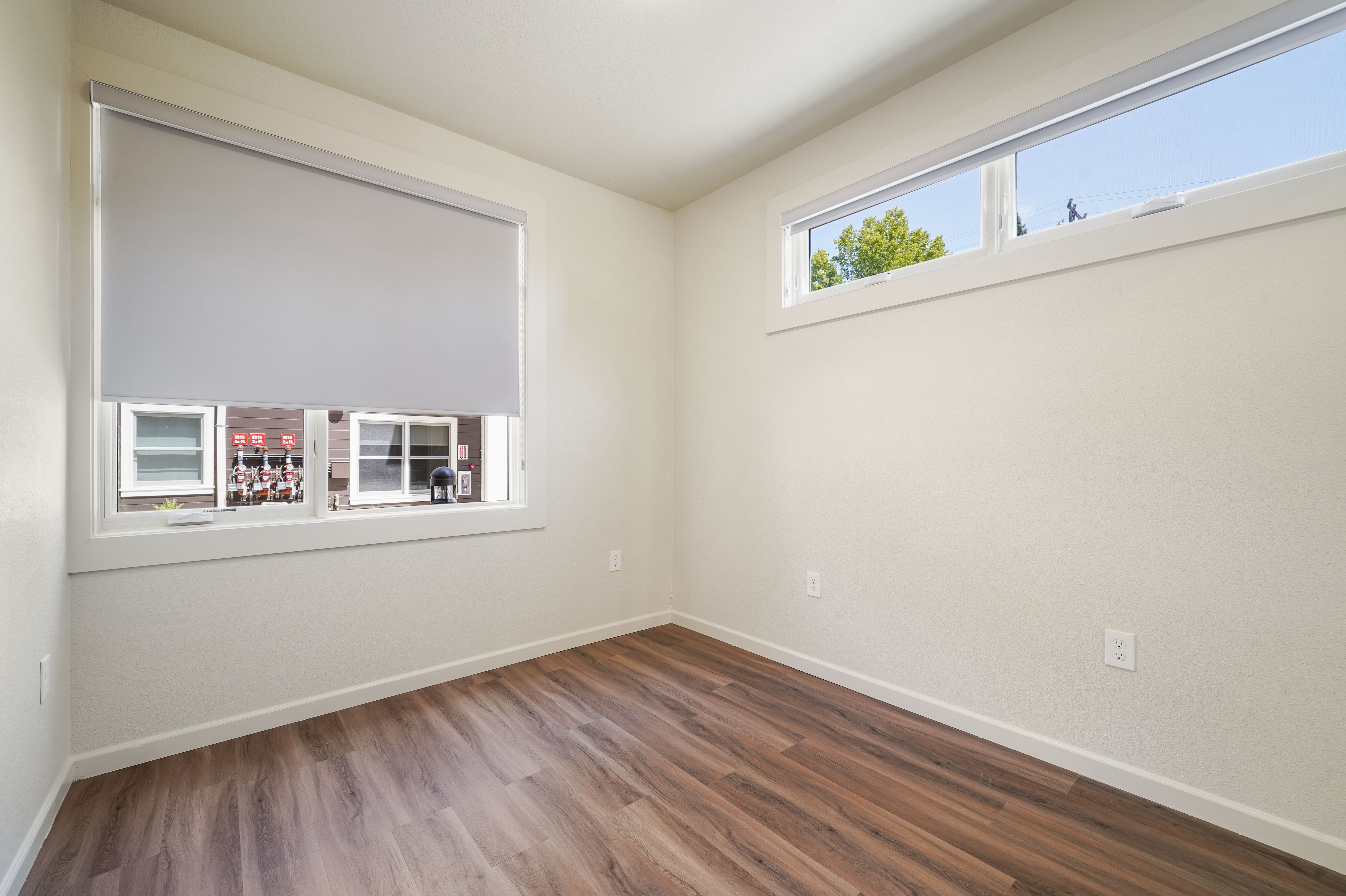 A room with a window and a wooden floor.
