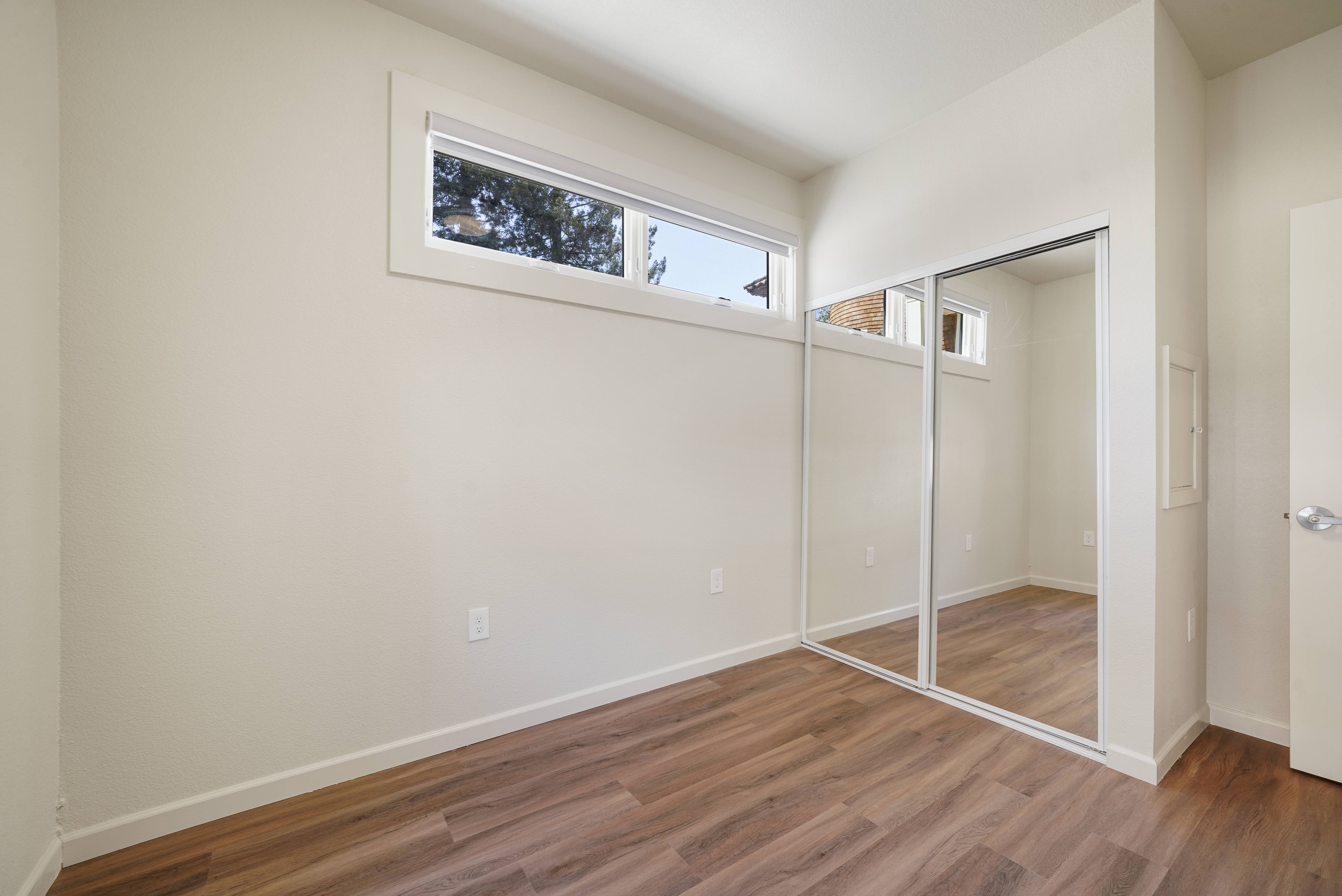 A room with a sliding glass door and wood flooring.