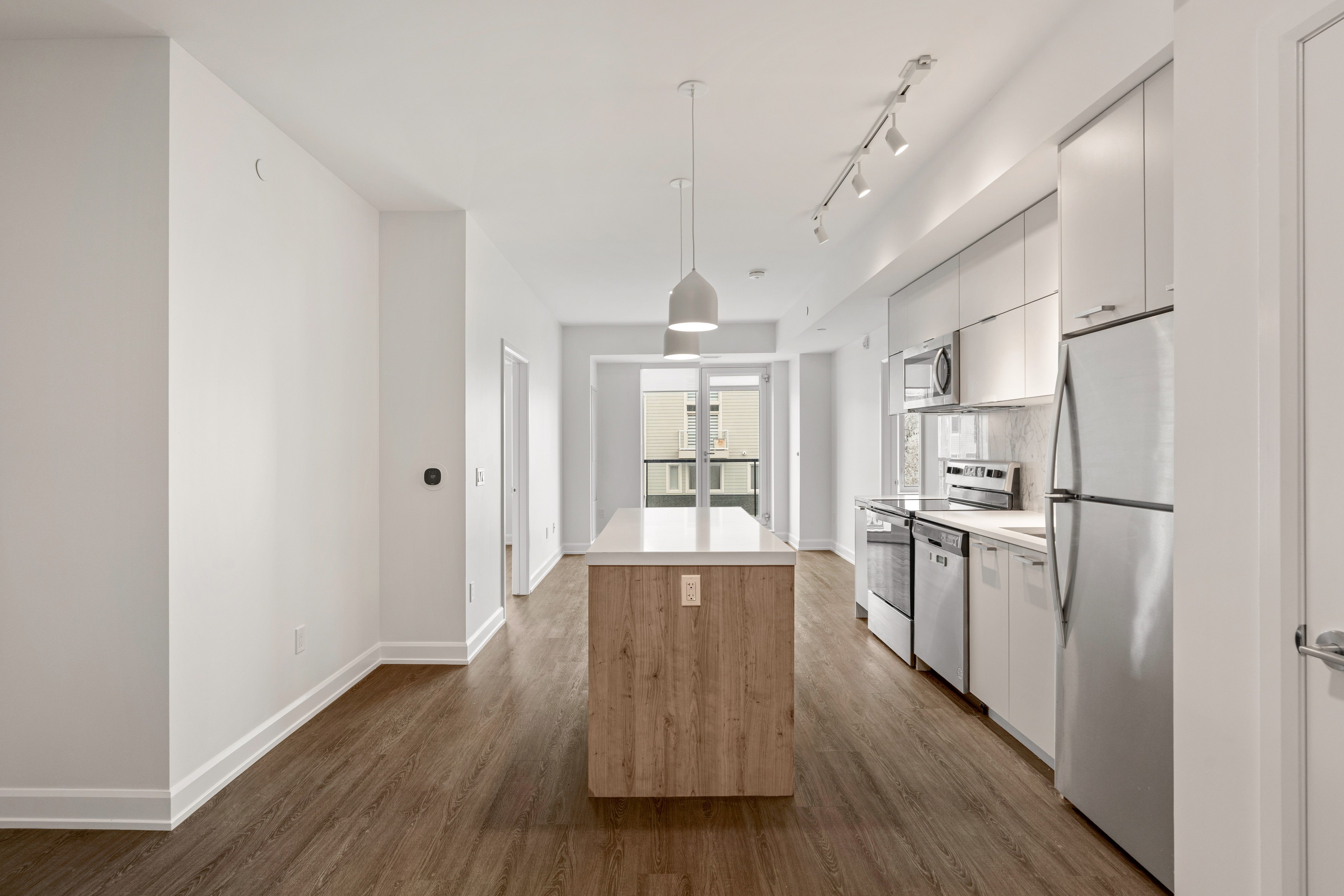 A modern kitchen with stainless steel appliances and wooden floors.