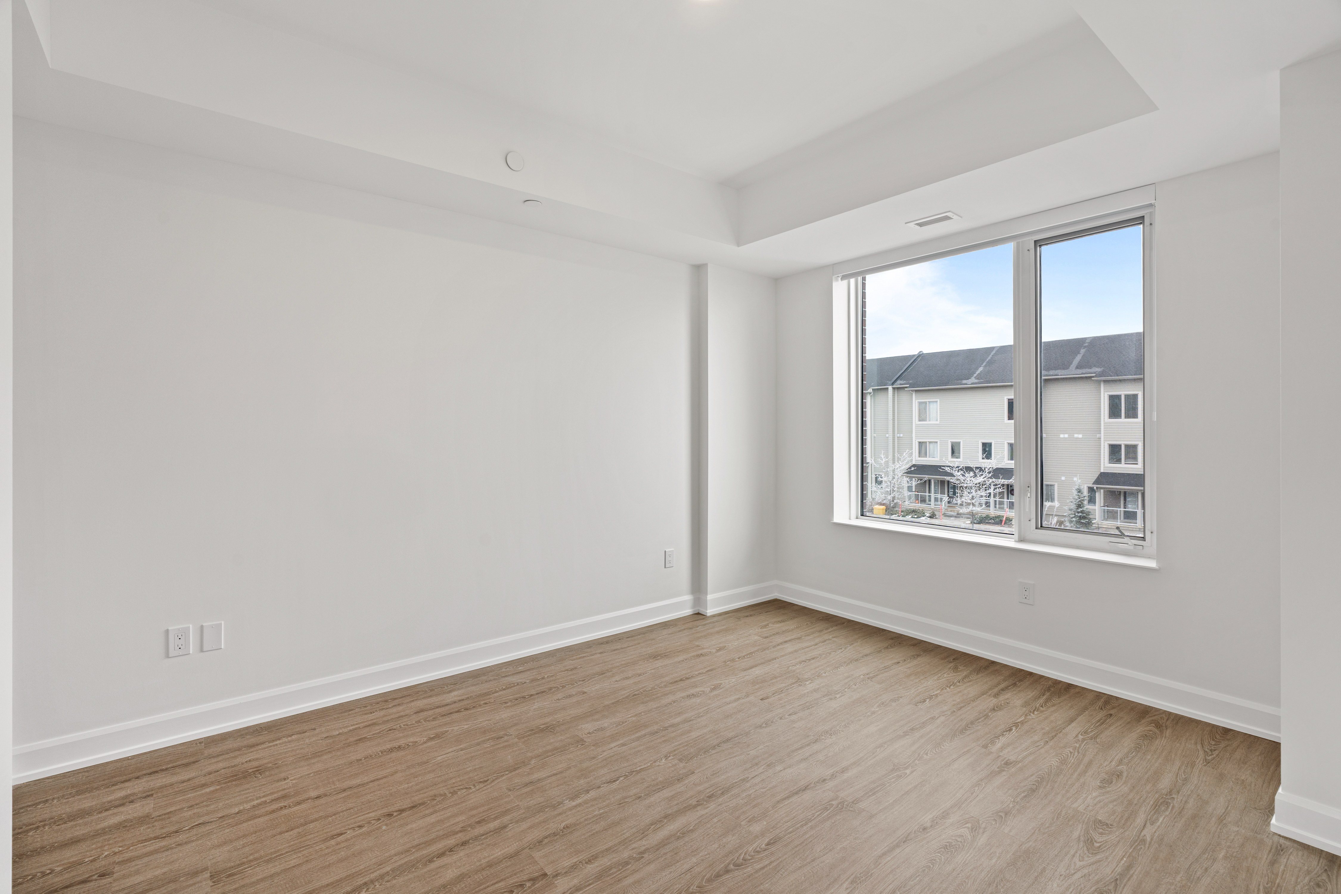 Empty room with a window showing a view of houses.
