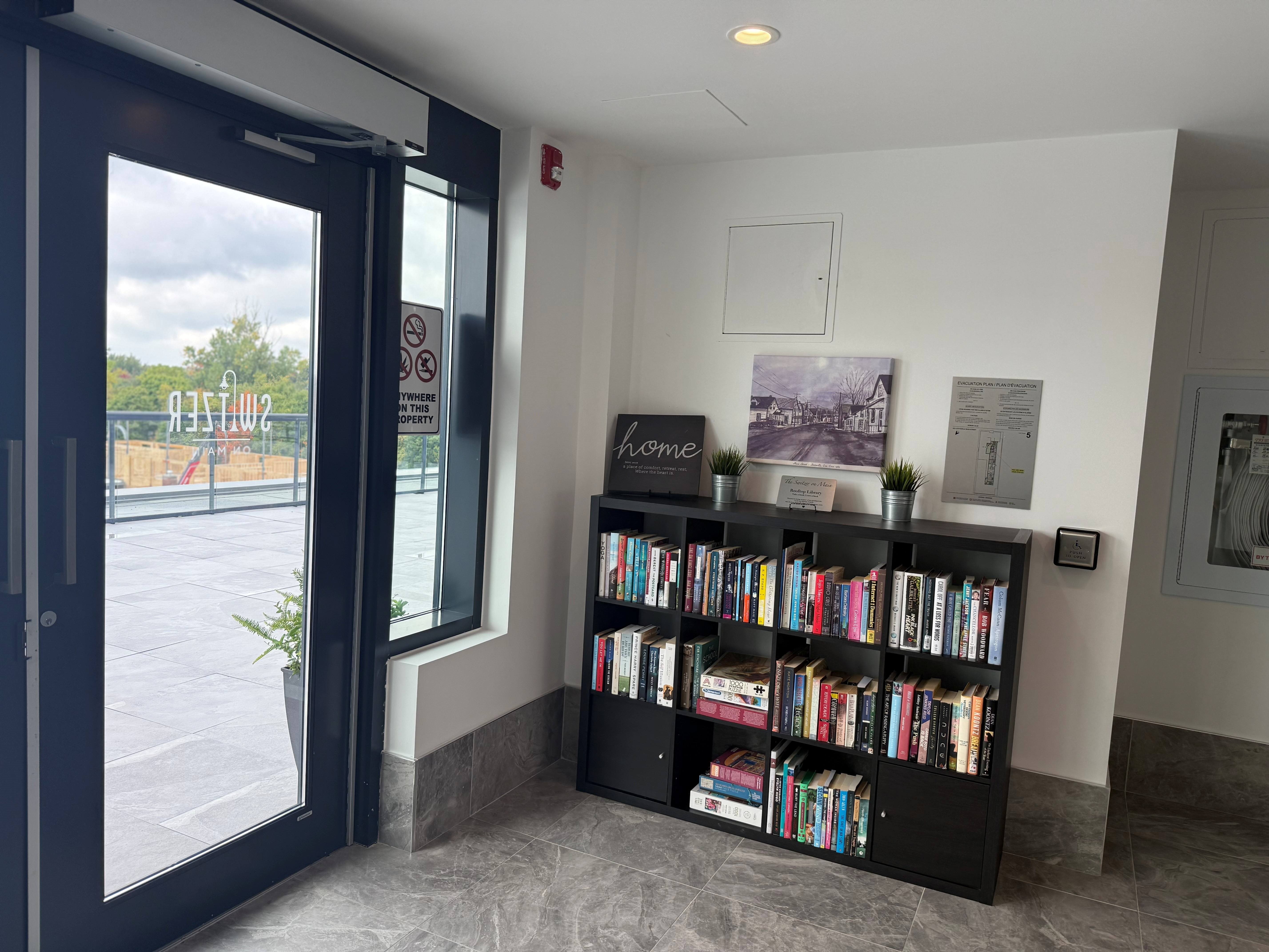 A black bookshelf filled with books in a room with a door and a window.