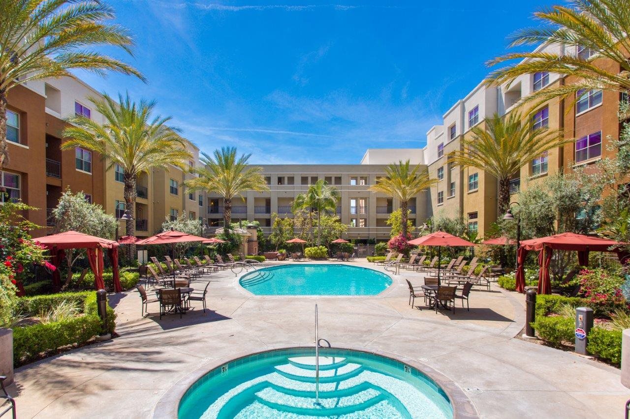 a swimming pool at a hotel with tables and umbrellas