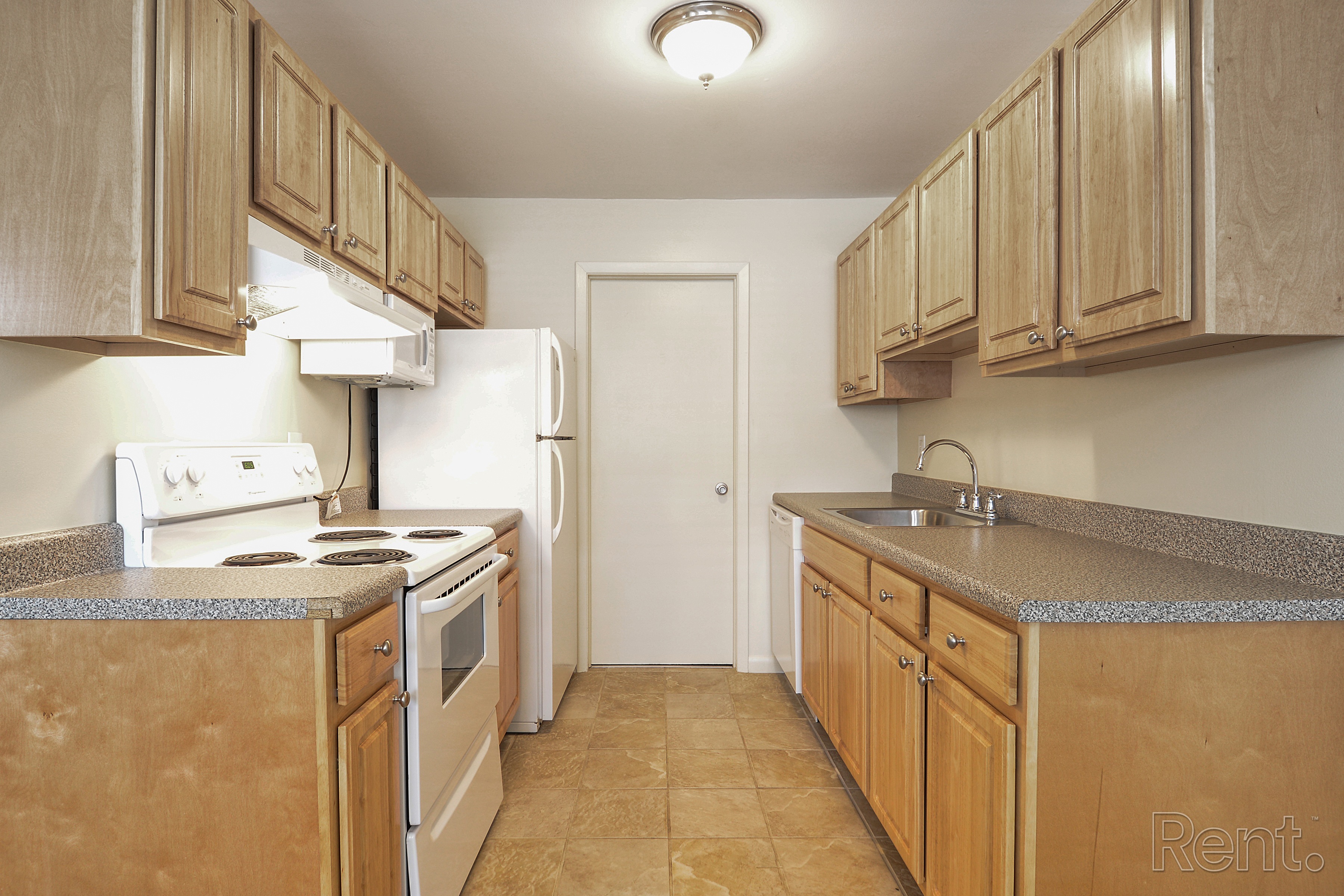 A kitchen with wooden cabinets and a white stove top oven.