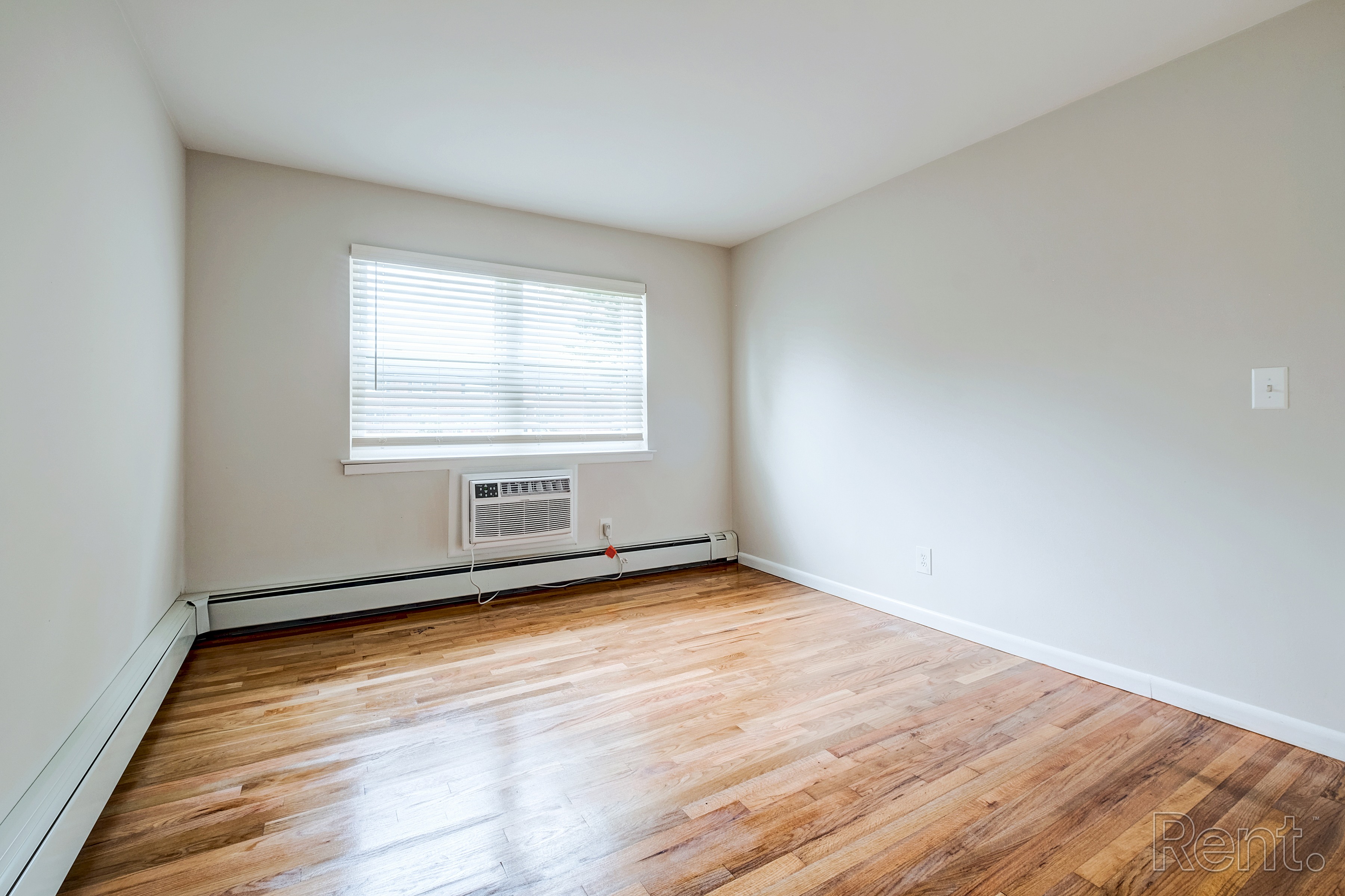 A room with wooden floors and a window with blinds.
