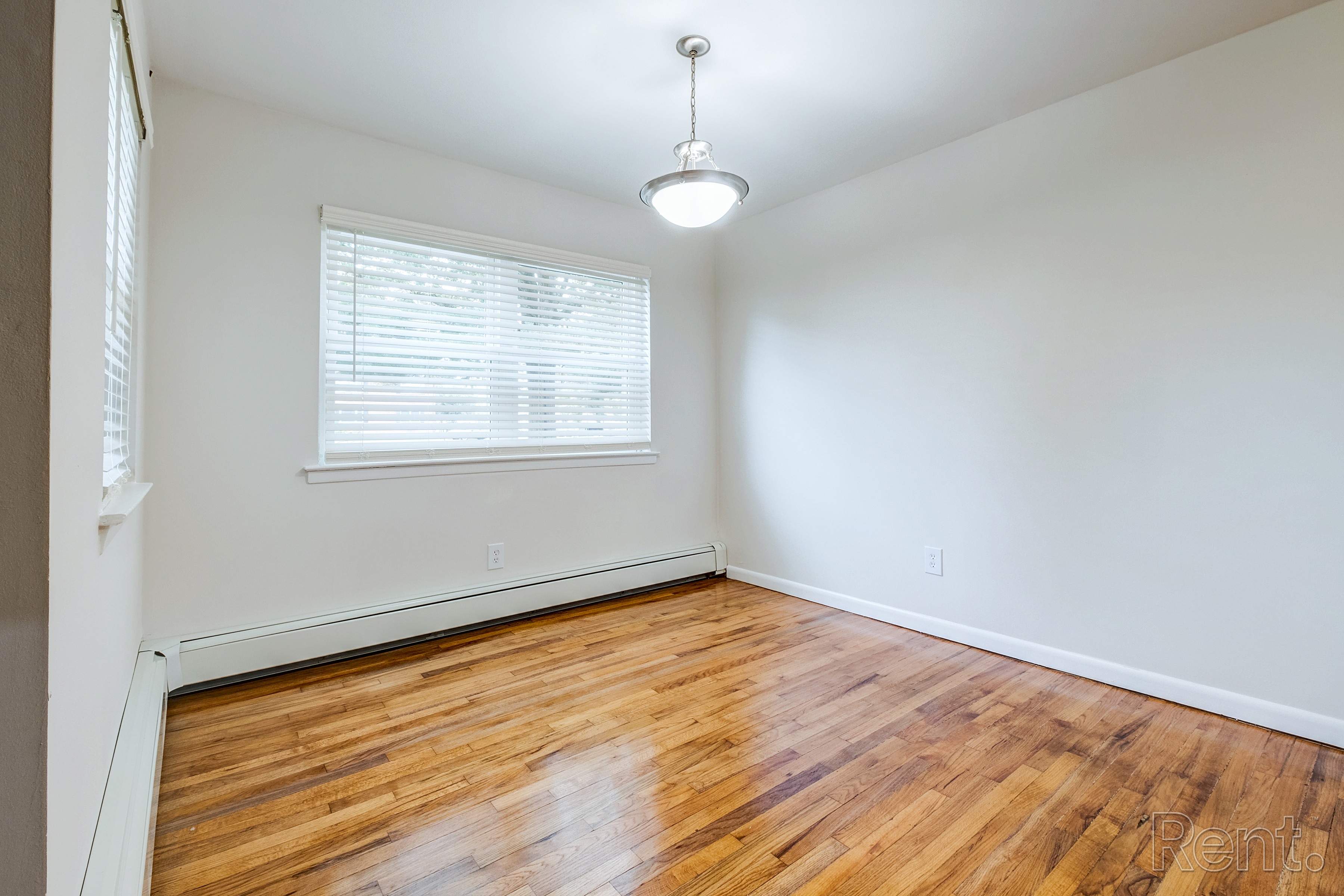 A room with wooden floors and a window with blinds.