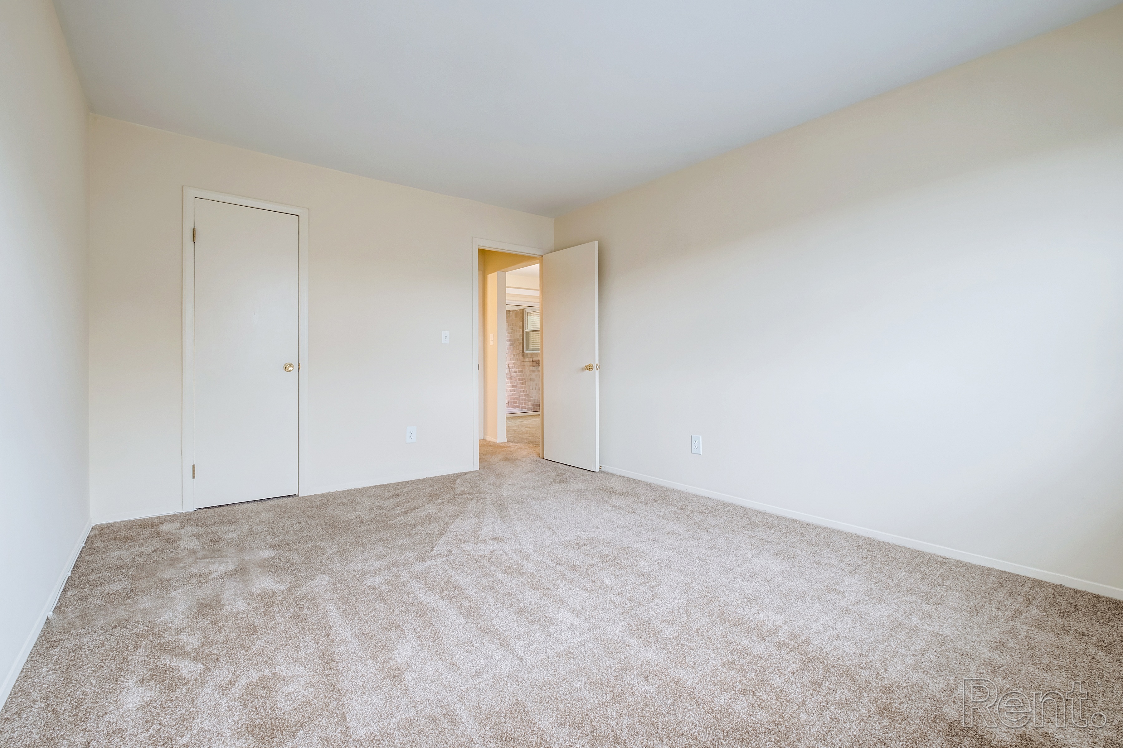 A room with a carpeted floor and two doors.