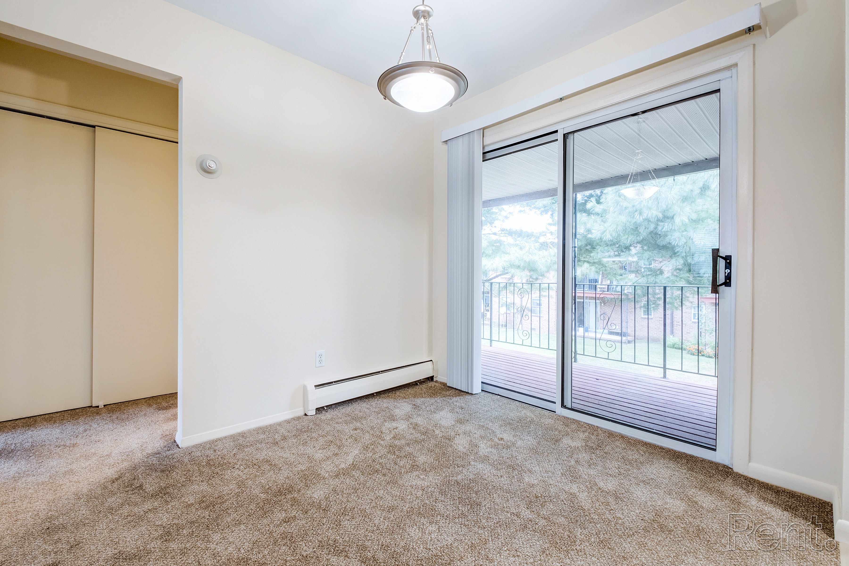 A room with a sliding glass door leading to a balcony.