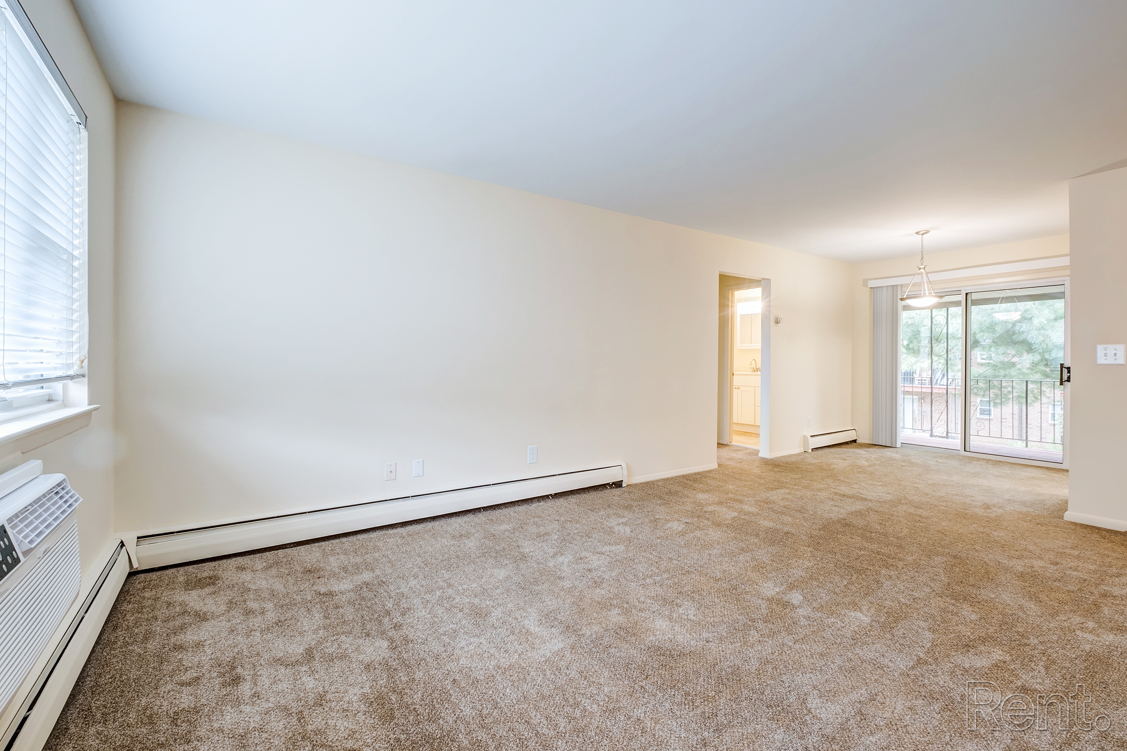 A room with a carpeted floor and a door leading to a balcony.